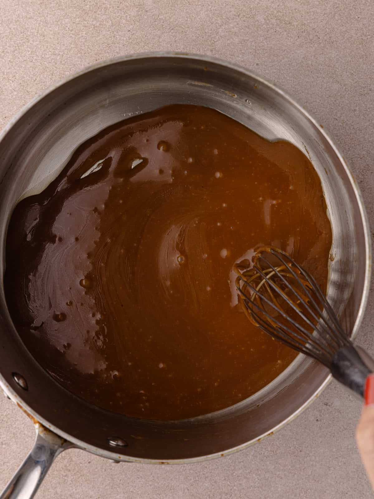 Butter and brown sugar are whisked in a small saucepan.