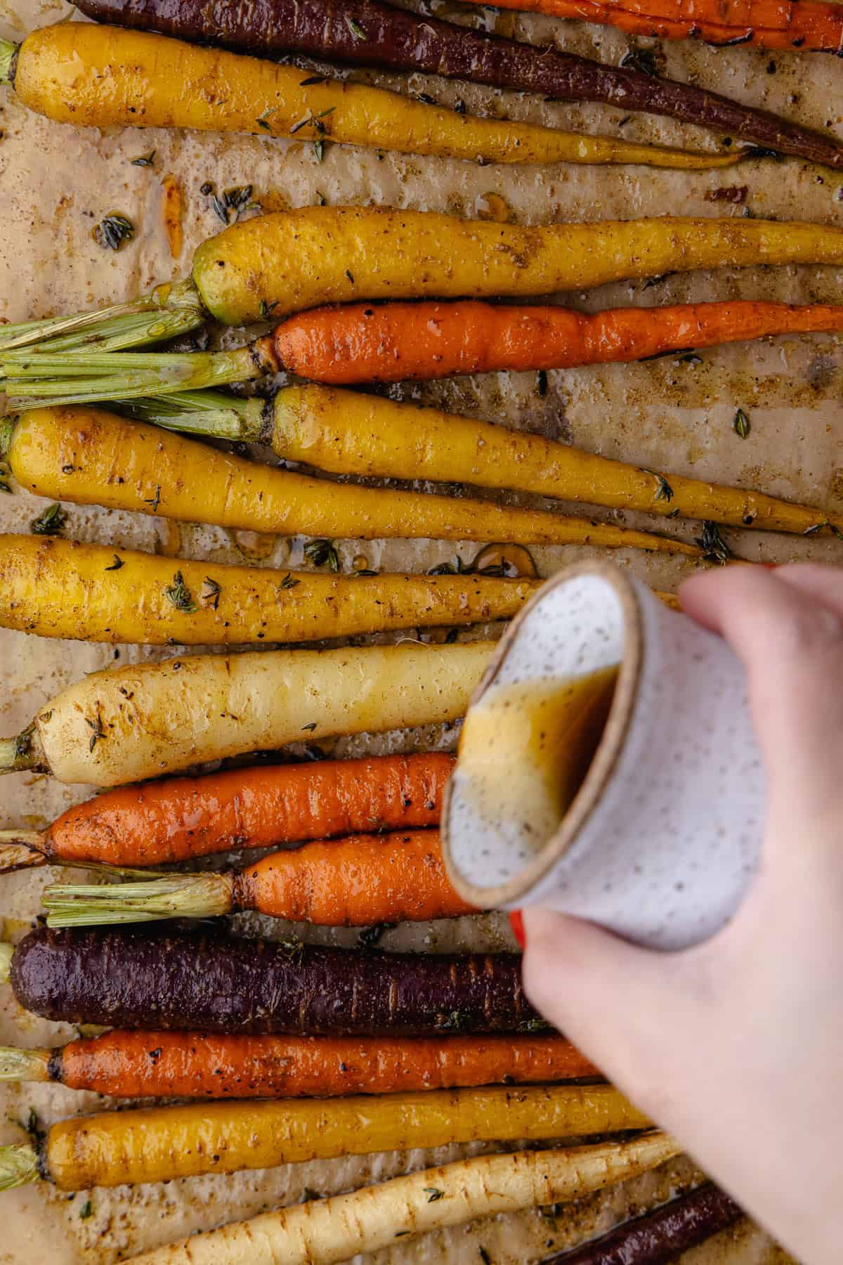 Maple syrup is drizzled on top of the roasted carrots.