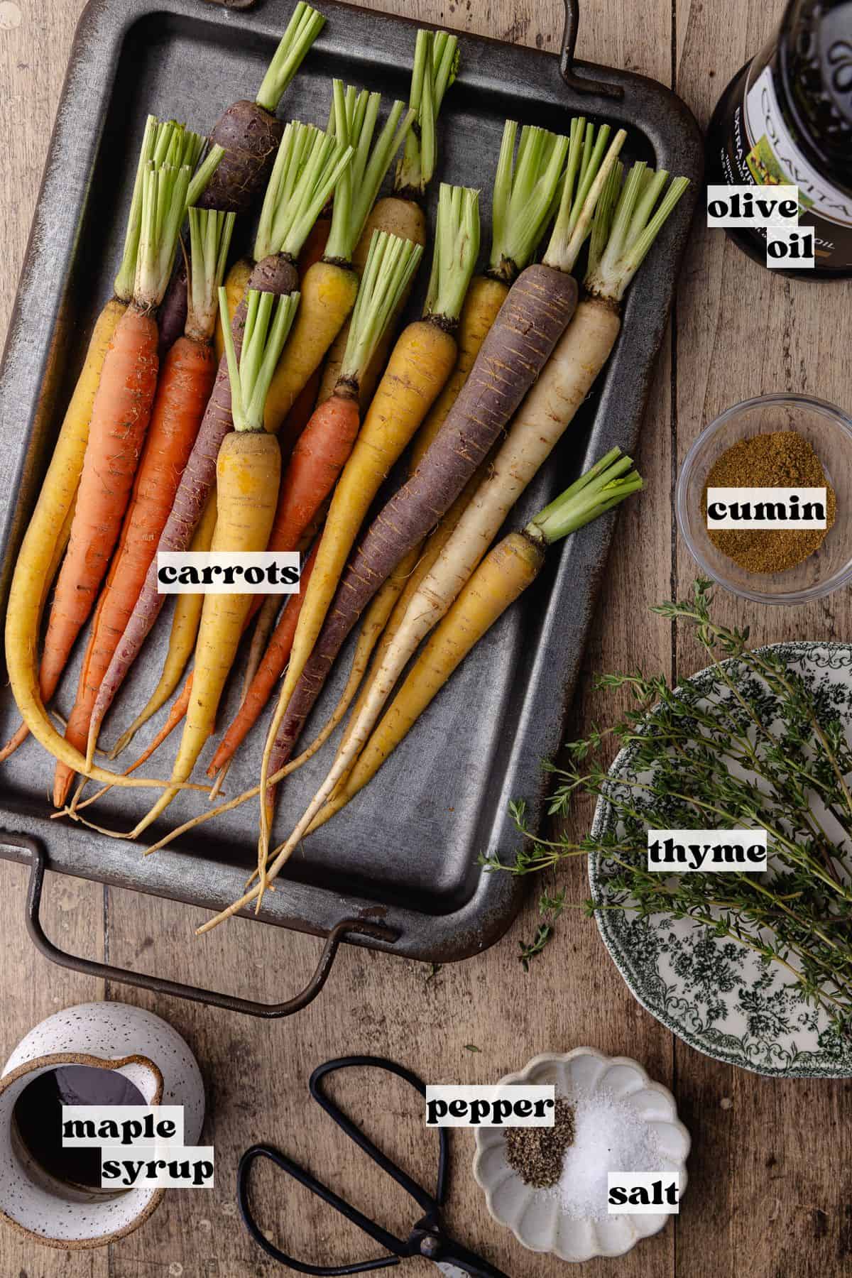 Ingredients for roasted carrots which include, rainbow carrots, extra-virgin olive oil, fresh thyme, cumin, salt, pepper and maple syrup.