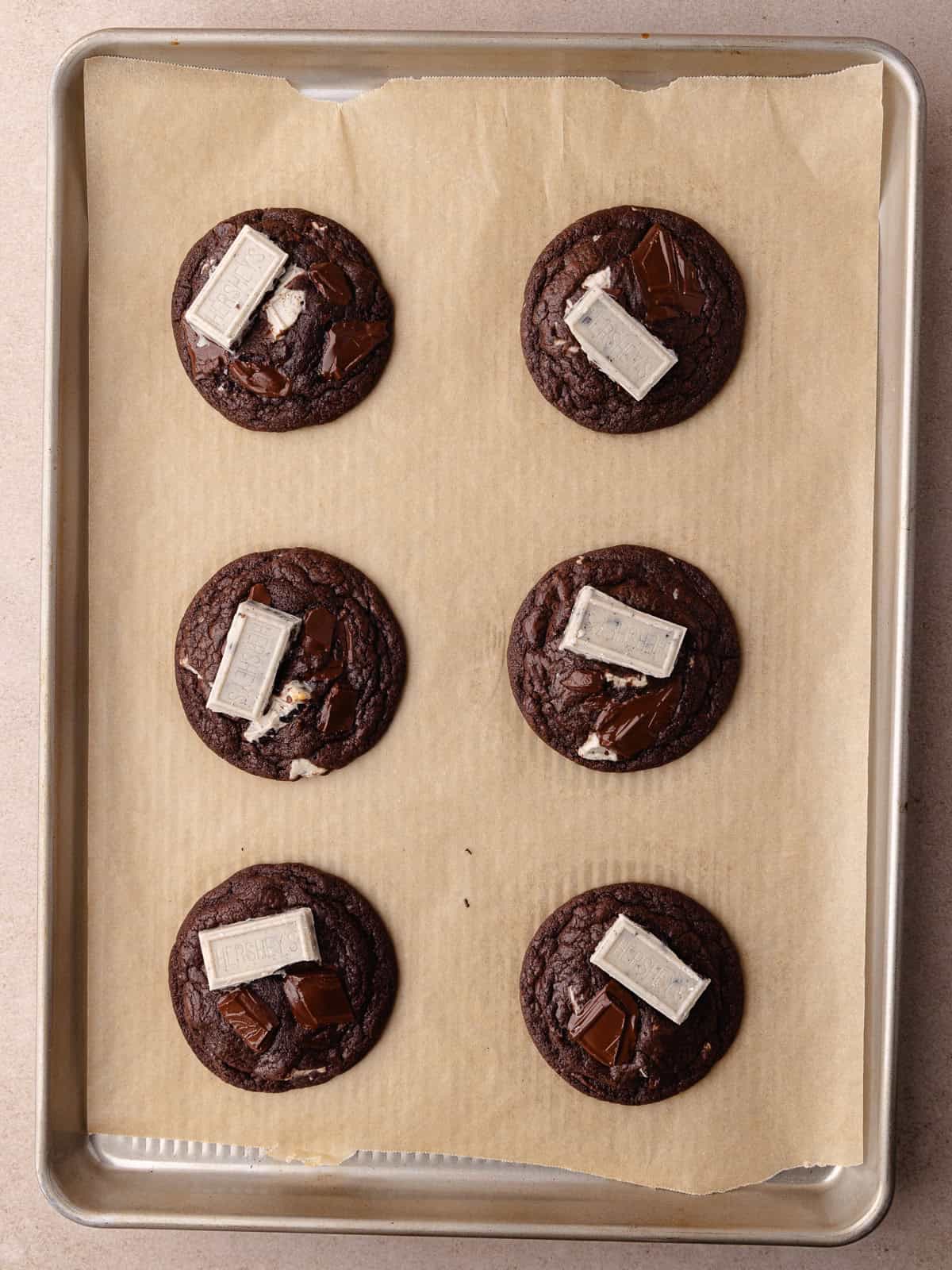 Chocolate cookies and cream cookies are sitting on a baking sheet.