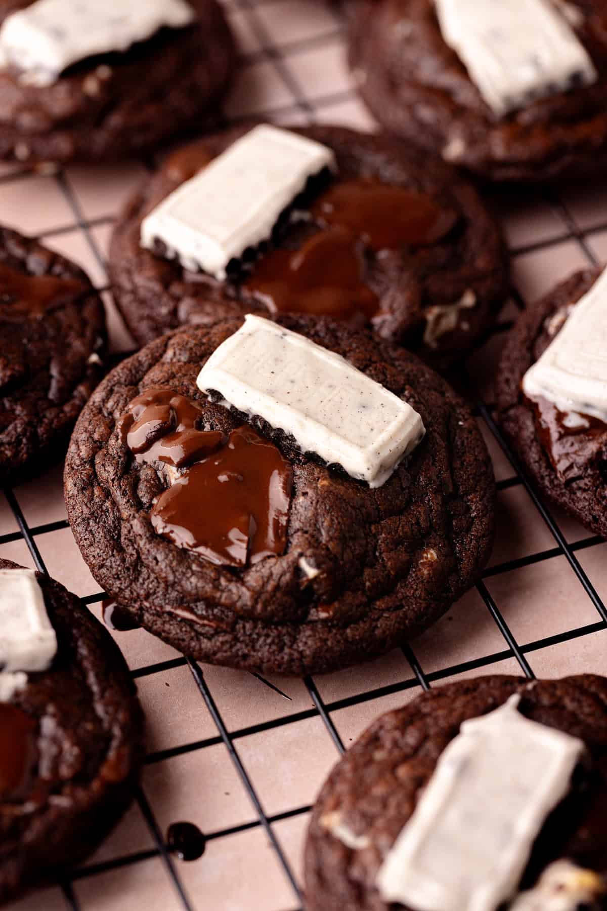 Chocolate cookies and cream cookies sitting on a wire rack.