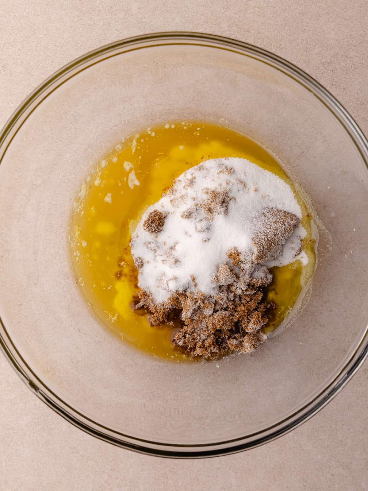 Melted butter, dark brown sugar and white sugar is added to a large glass bowl.