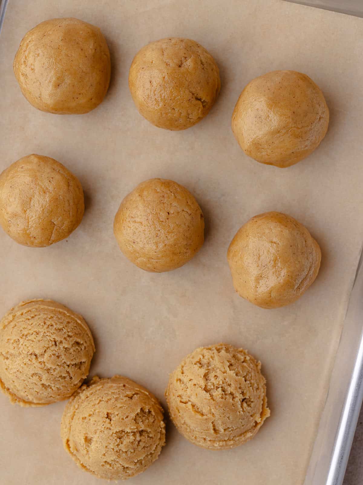 Cinnamon toast crunch cookie dough is scooped onto a small baking sheet lined with parchment paper.