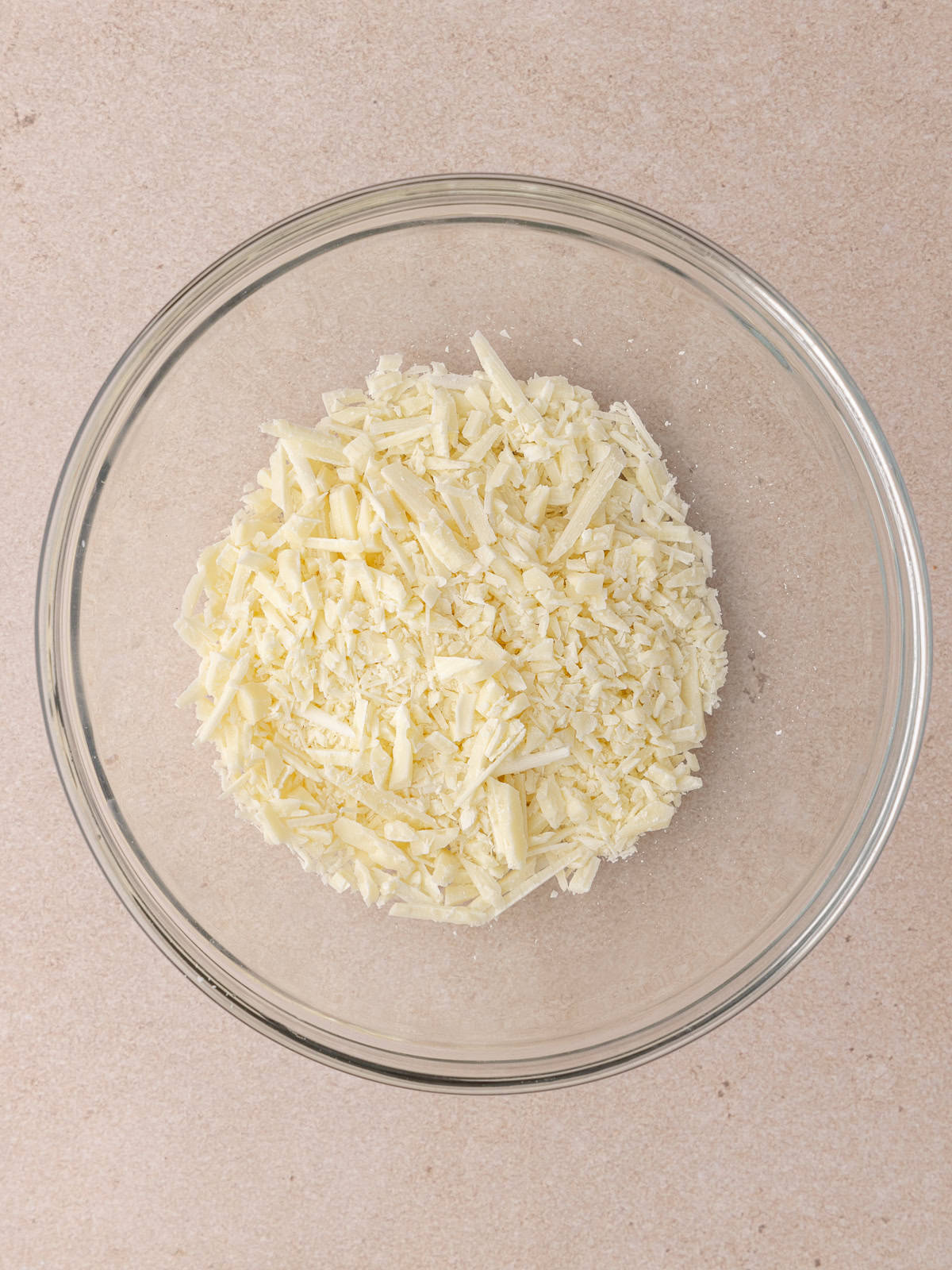 Finely chopped white chocolate are in a small glass bowl.