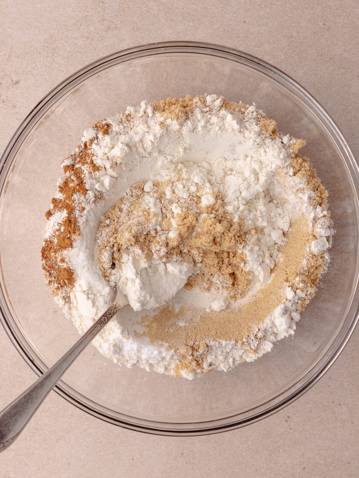 Dry ingredients are mixed together in a glass mixing bowl.