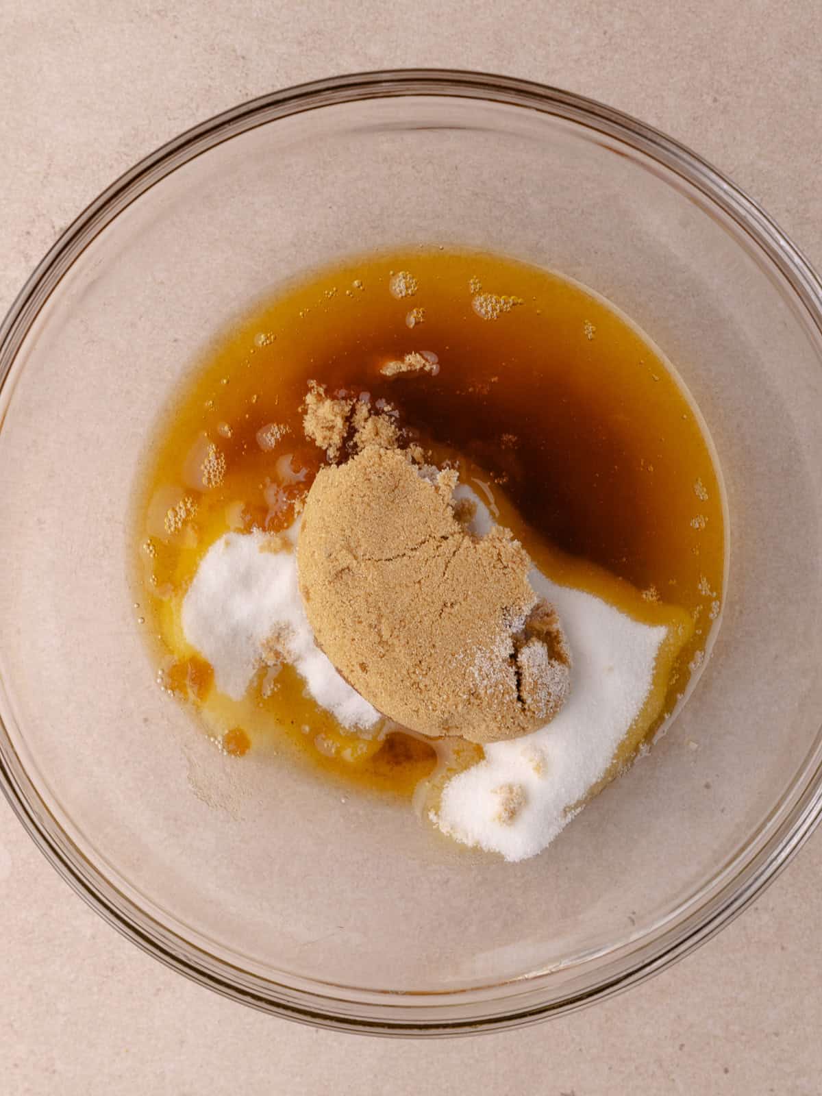 Brown butter, white sugar and brown sugar are in a glass mixing bowl.