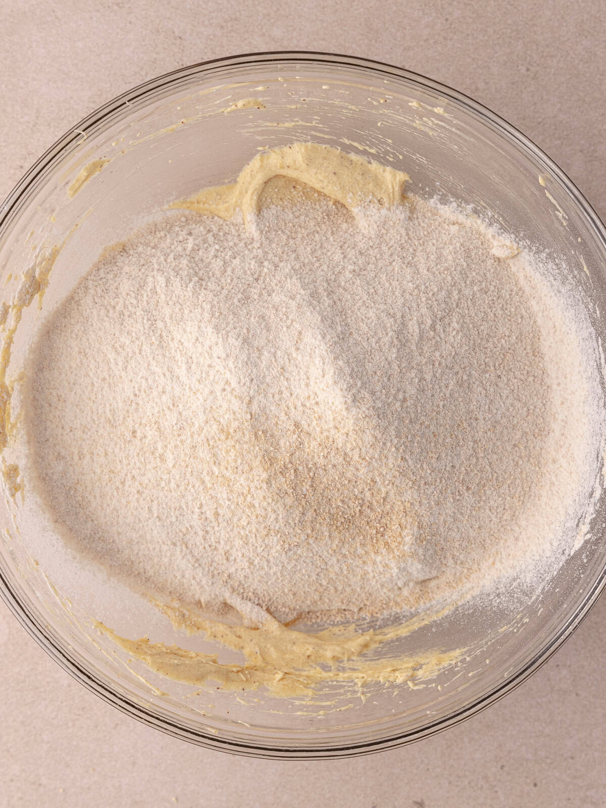 Dry ingredients are sifted into a bowl with wet ingredients.