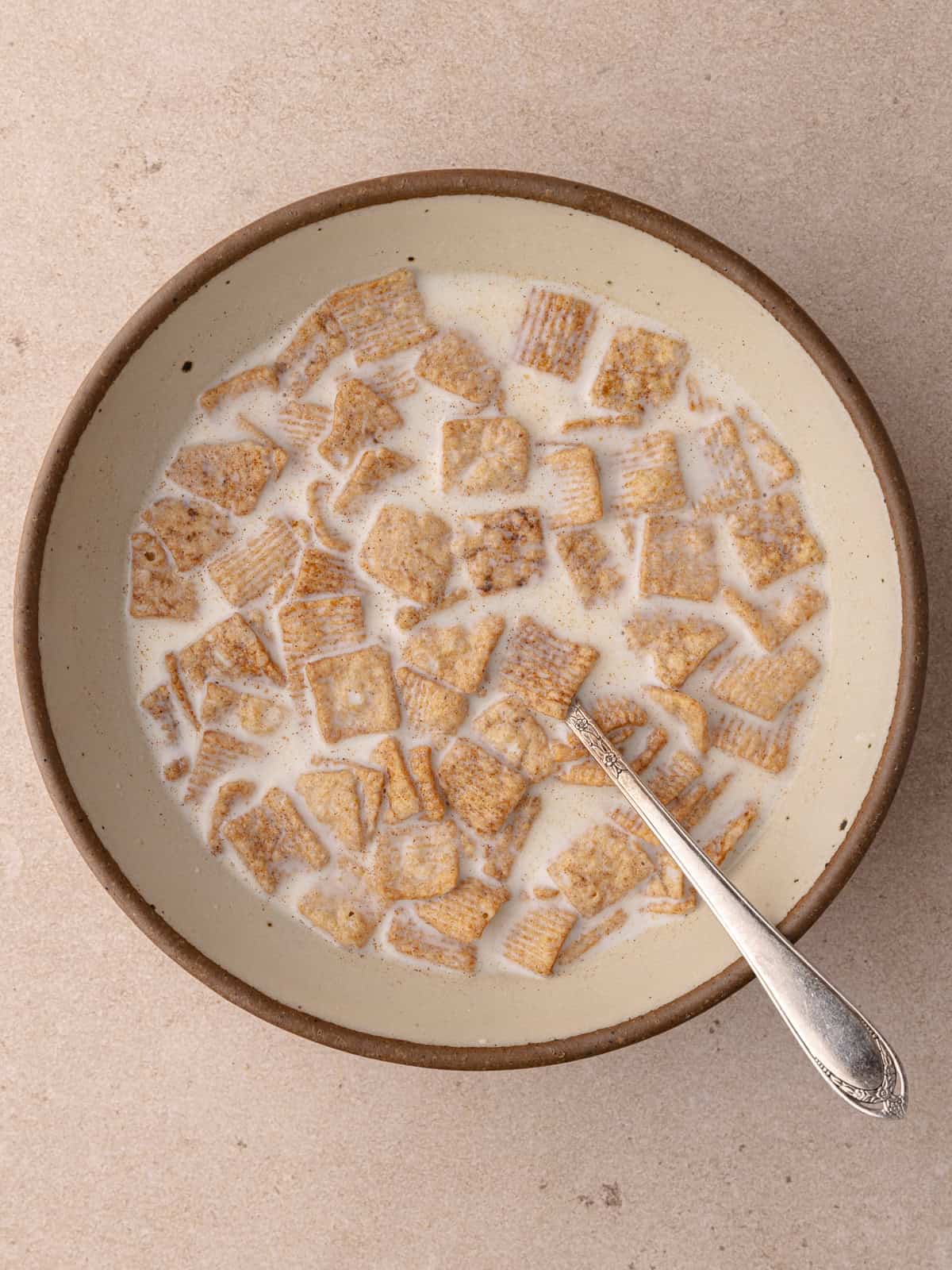 Cinnamon toast crunch cereal and milk is soaking in a bowl.