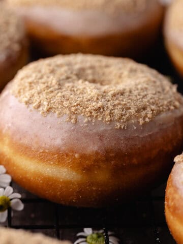 Glazed cinnamon toast crunch donuts sitting on a wire rack featured photo.