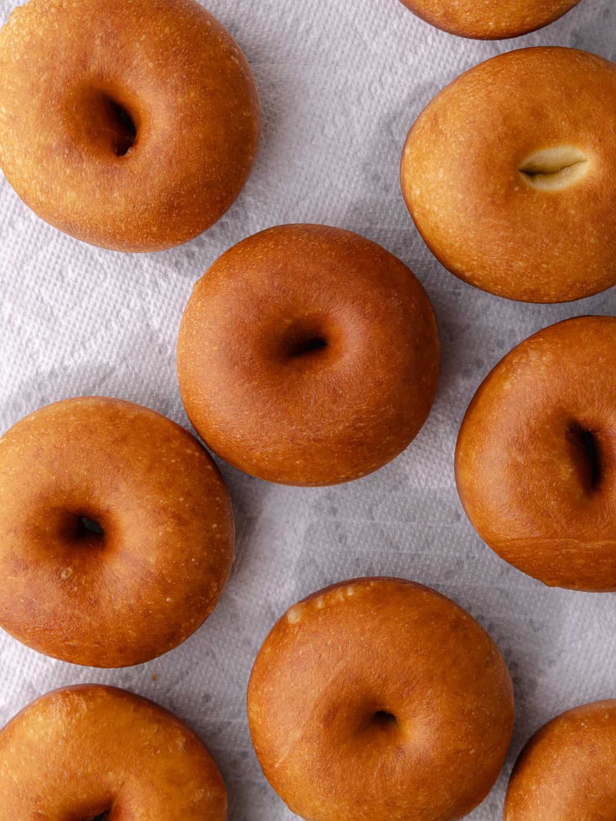 Donuts are fries until golden brown and sitting on a paper towel-lined baking sheet.