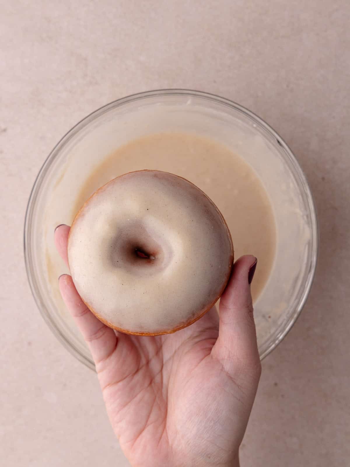 A donut is dipped in the cereal milk glaze.