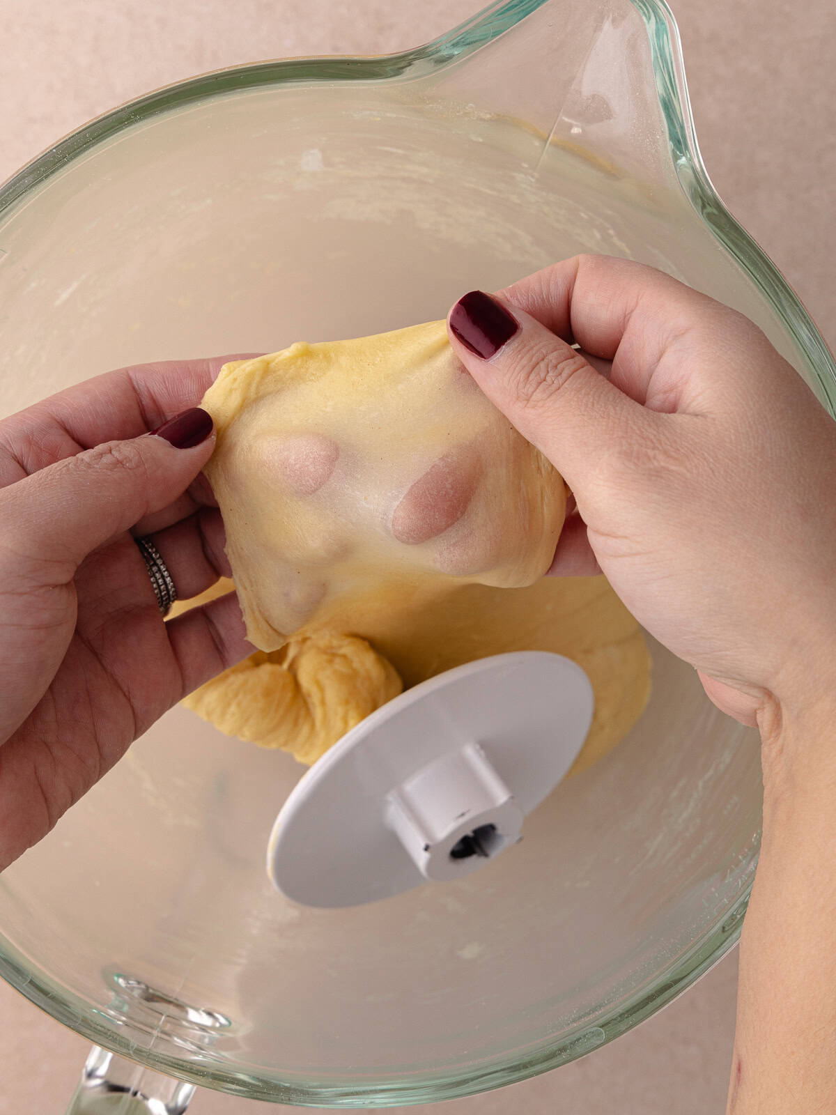 Cinnamon toast crunch donut dough is stretched thin enough to let light pass through. A window pane test is performed to check if dough is done kneading.