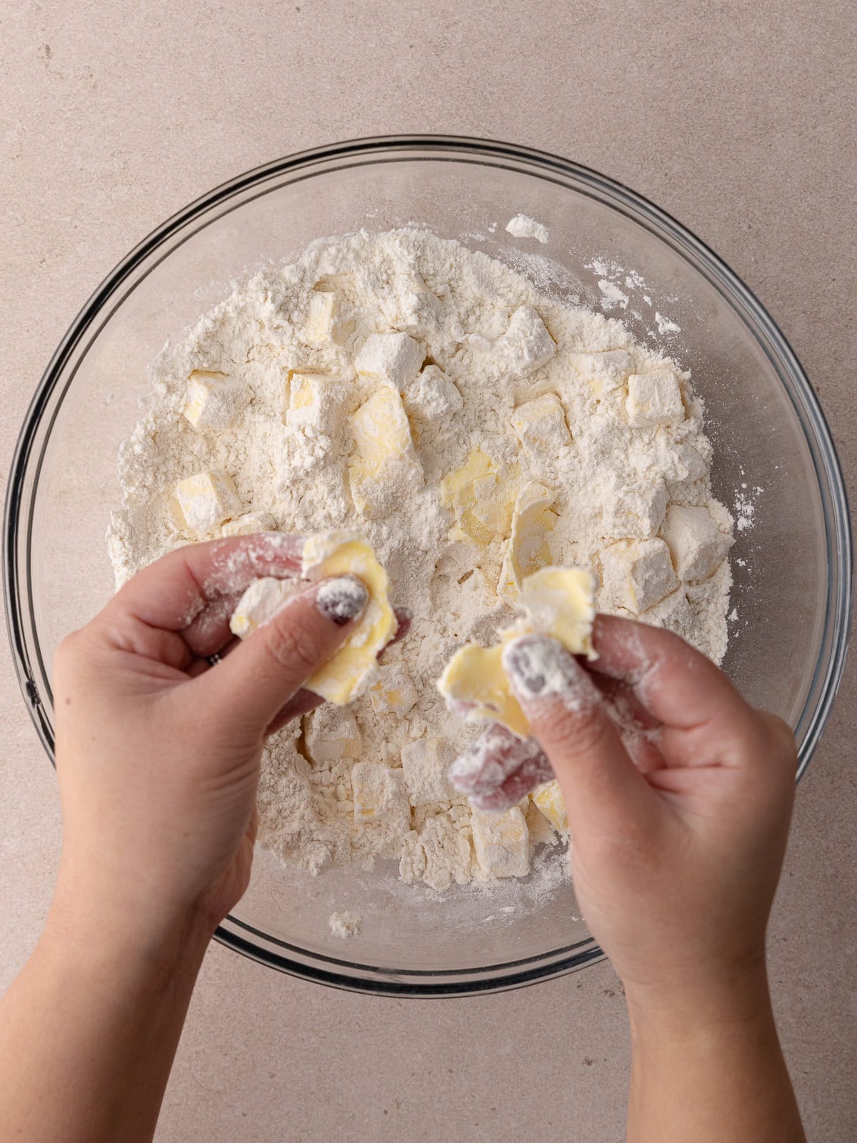 Cubes of butter are squeezed in between the fingers and flour to flatten into flat discs.