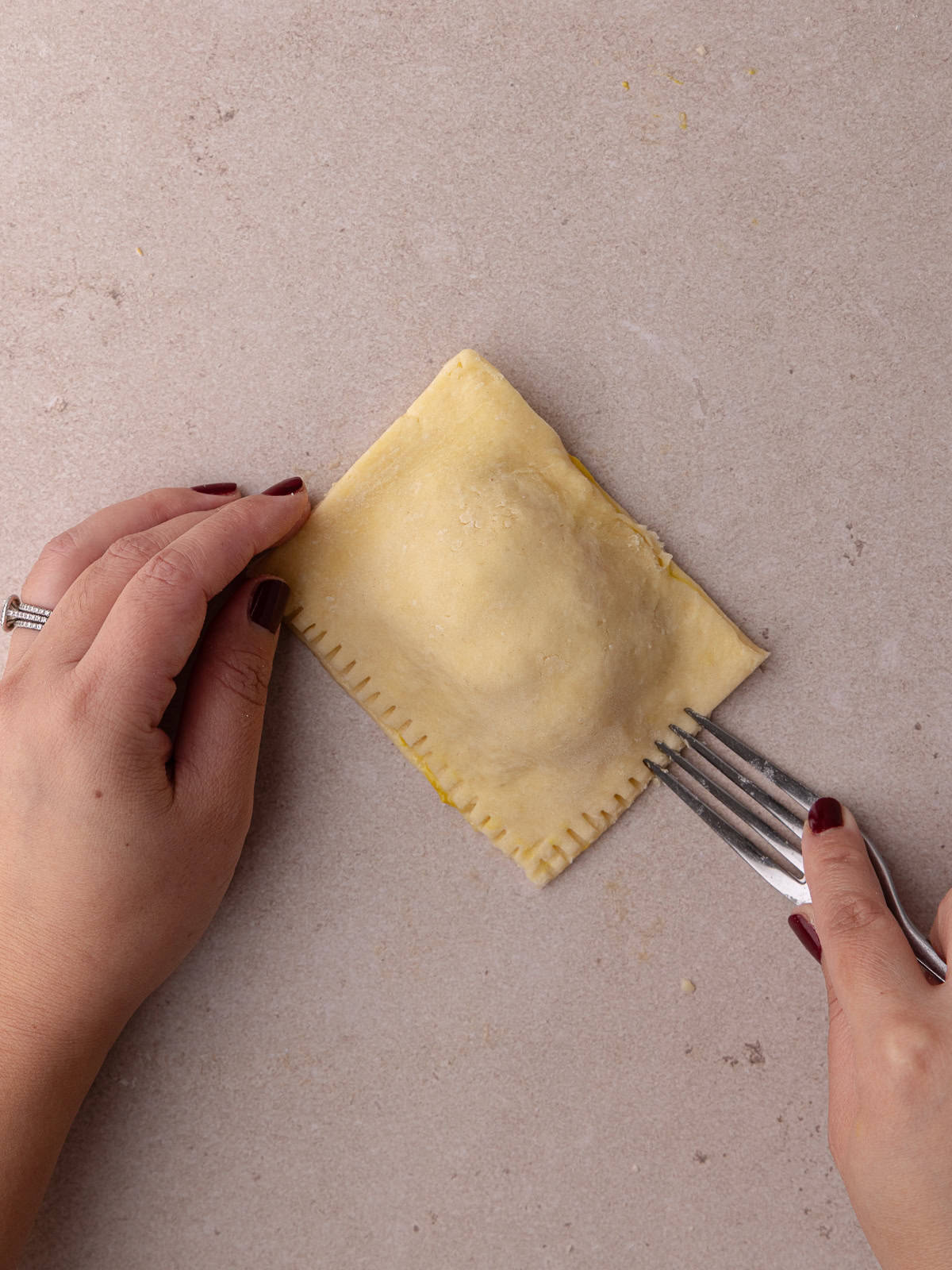 Super flaky and tender ham and cheese hand pie edge is crimped with a fork.