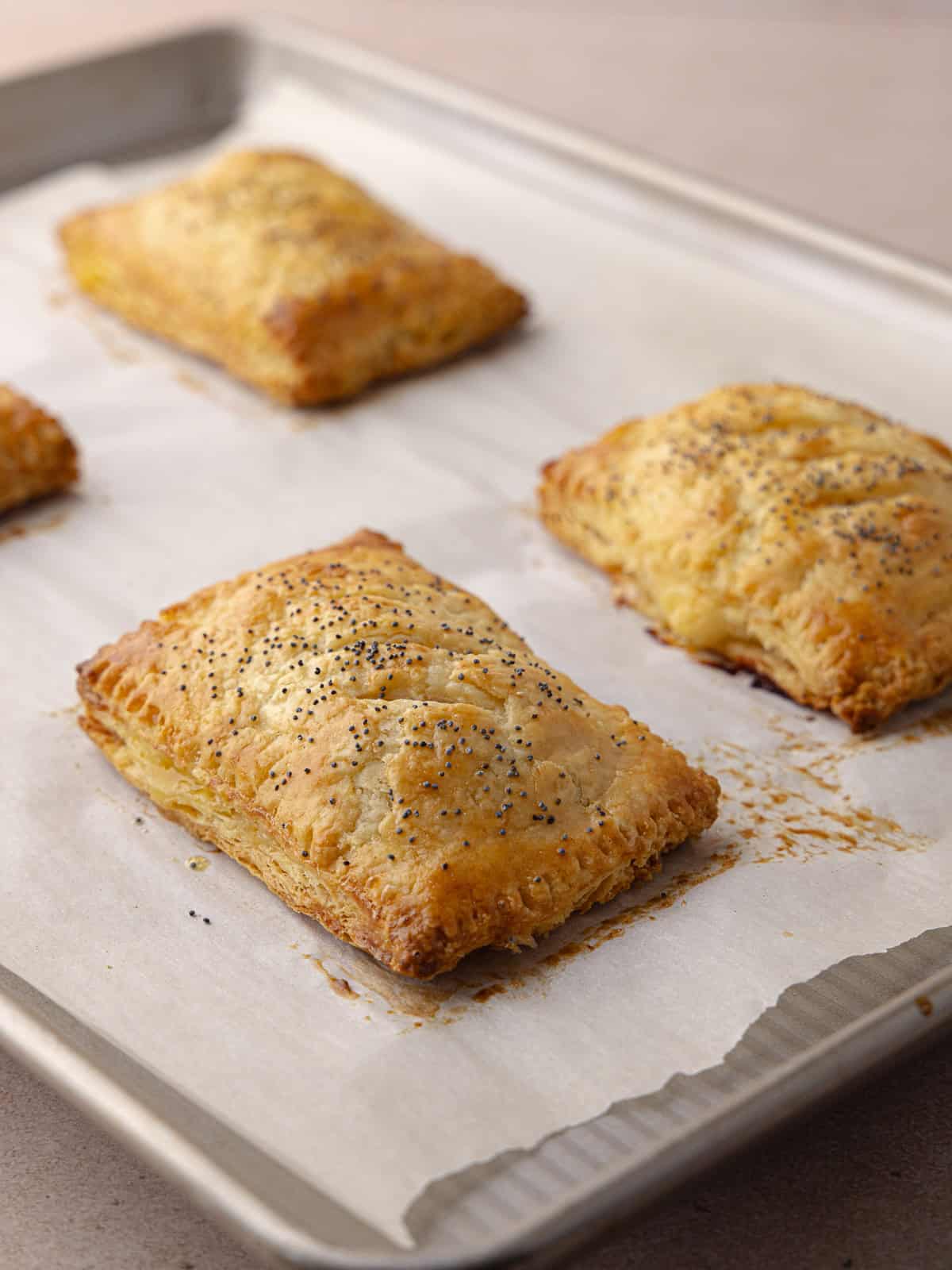 Super flaky and tender ham and cheese hand pies sitting on baking sheet baked golden brown.