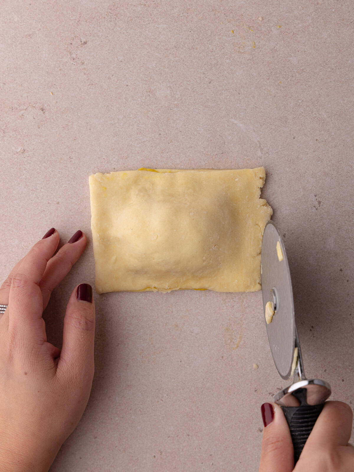 Pizza cutter cuts off the irregular edges of the ham and cheese hand pie.