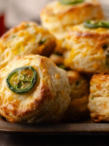 Tall flaky buttermilk Jalapeño cheddar biscuits sitting on a serving tray feature photo.