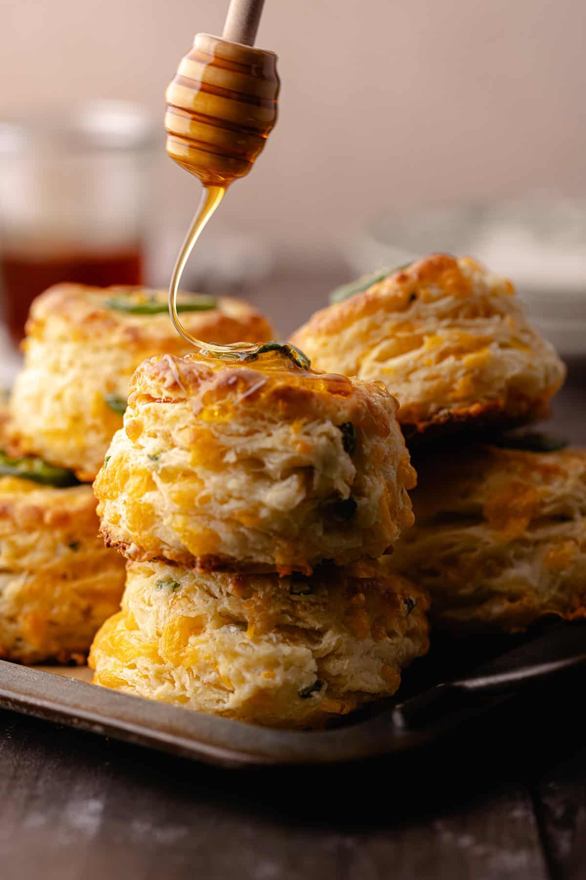 Jalapeño cheddar biscuits drizzled with hot honey sitting on a serving tray.