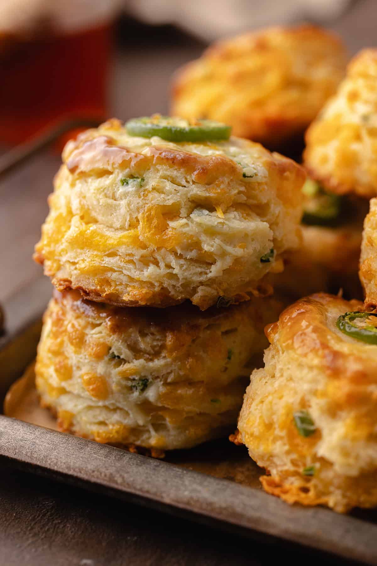 Tall flaky buttermilk Jalapeño cheddar biscuits sitting on a serving tray.