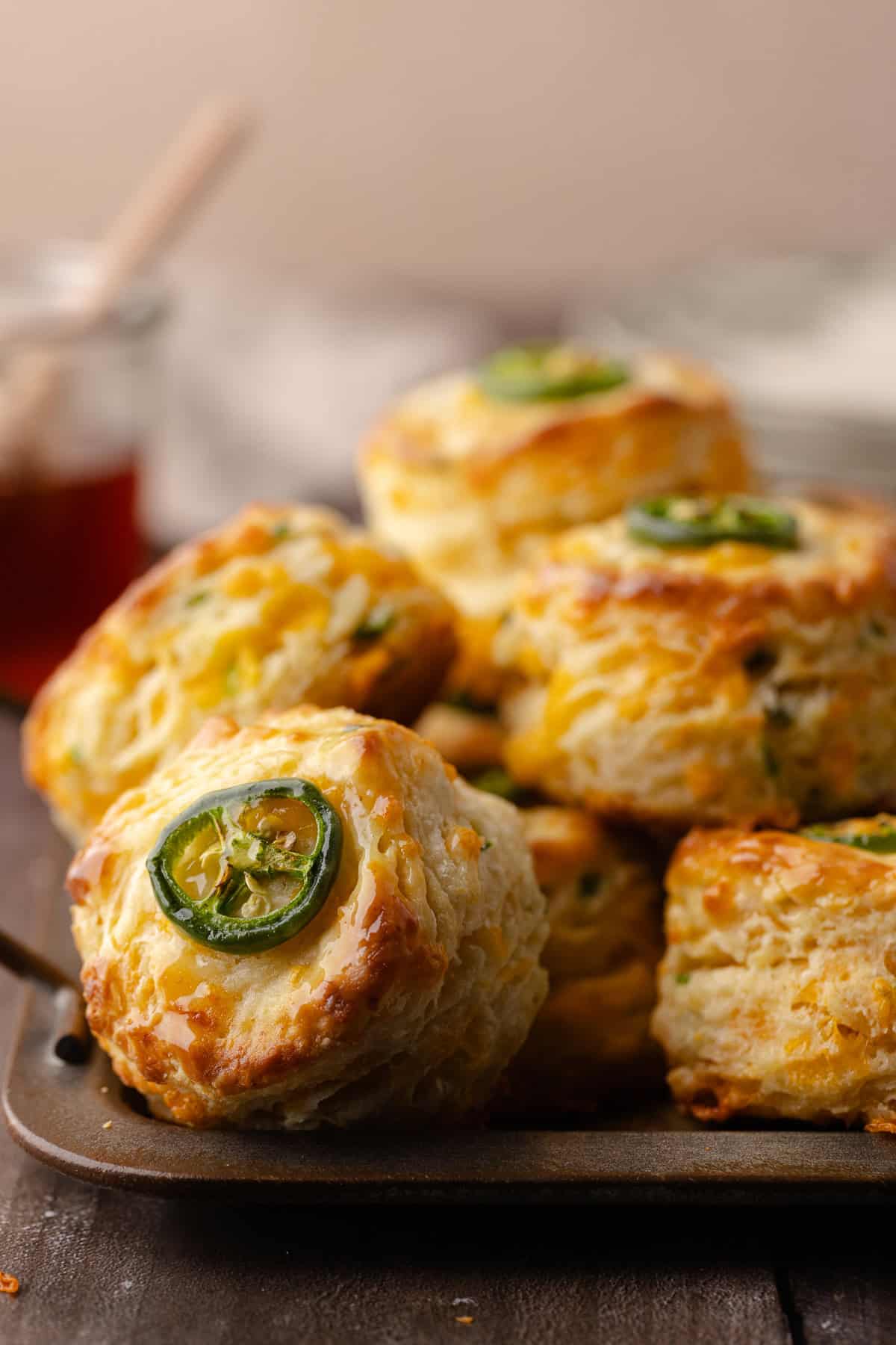 Tall flaky buttermilk Jalapeño cheddar biscuits sitting on a serving tray.