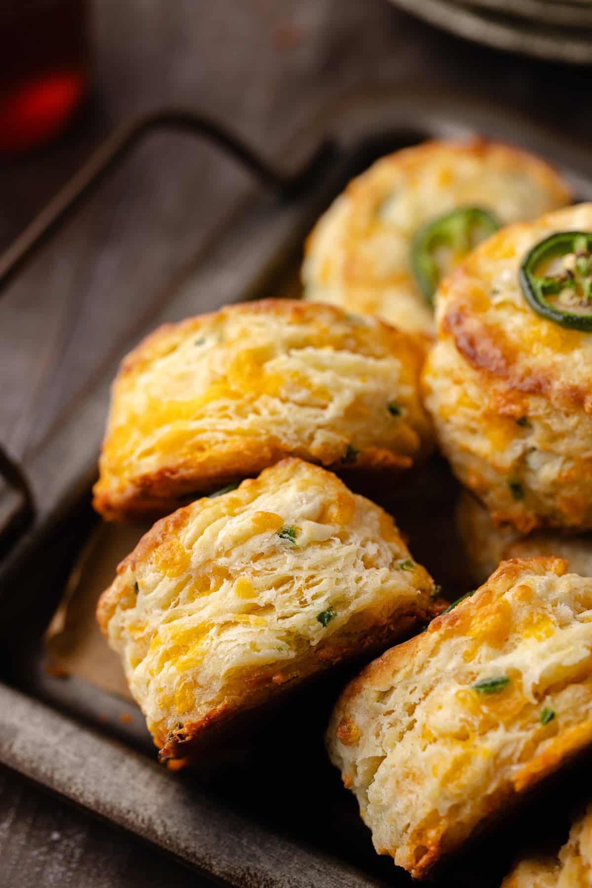 Tall flaky buttermilk Jalapeño cheddar biscuits sitting on a serving tray.