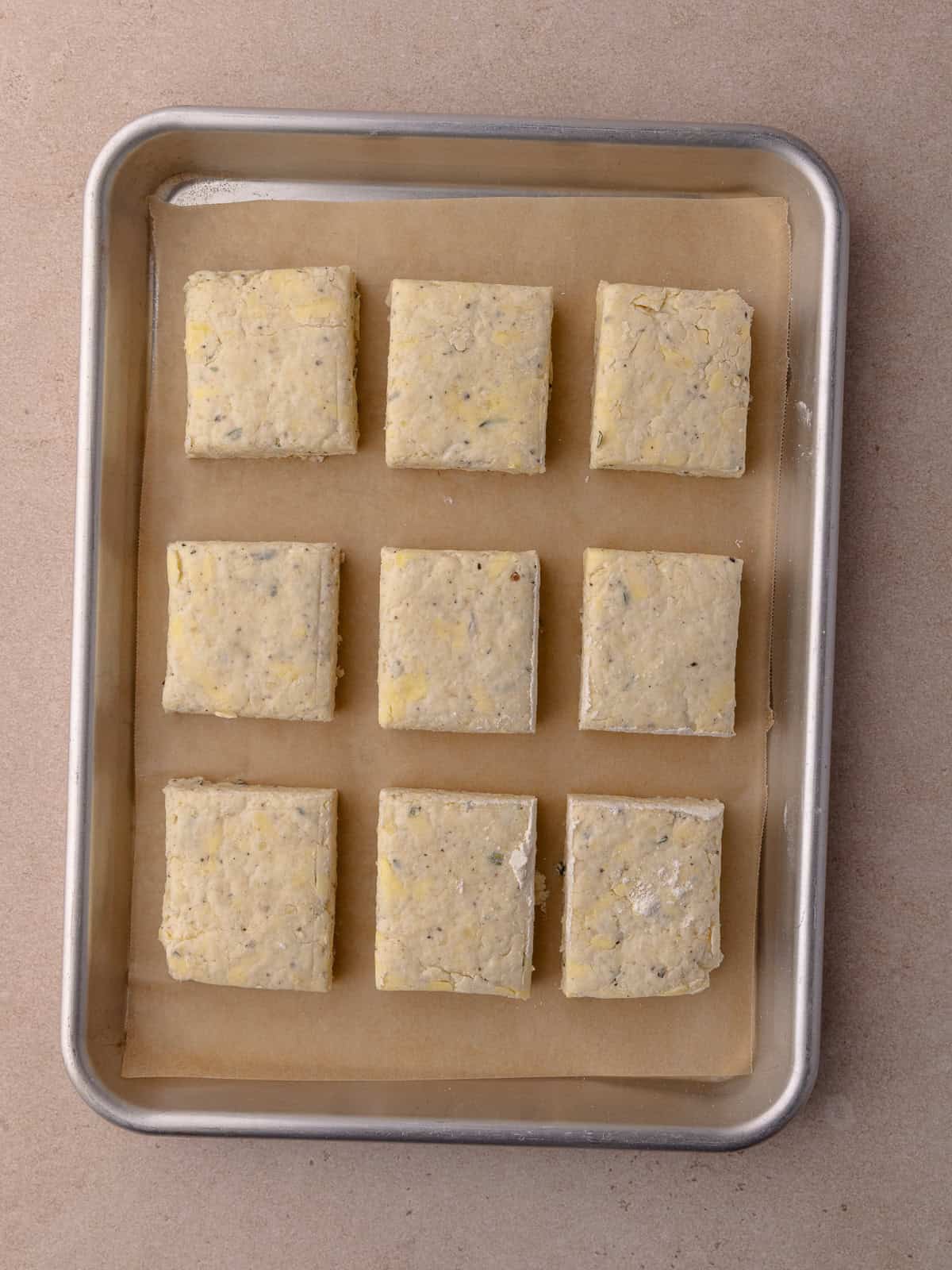 The cut biscuits are transferred to a small baking tray lined with parchment paper.