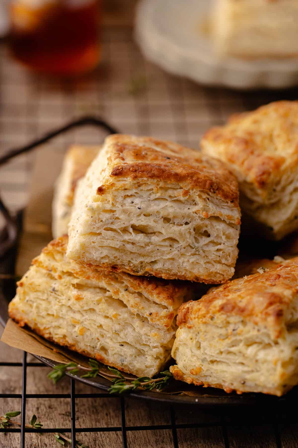 Tall and flaky Parmesan Black Pepper Thyme Biscuits sitting on a serving tray.