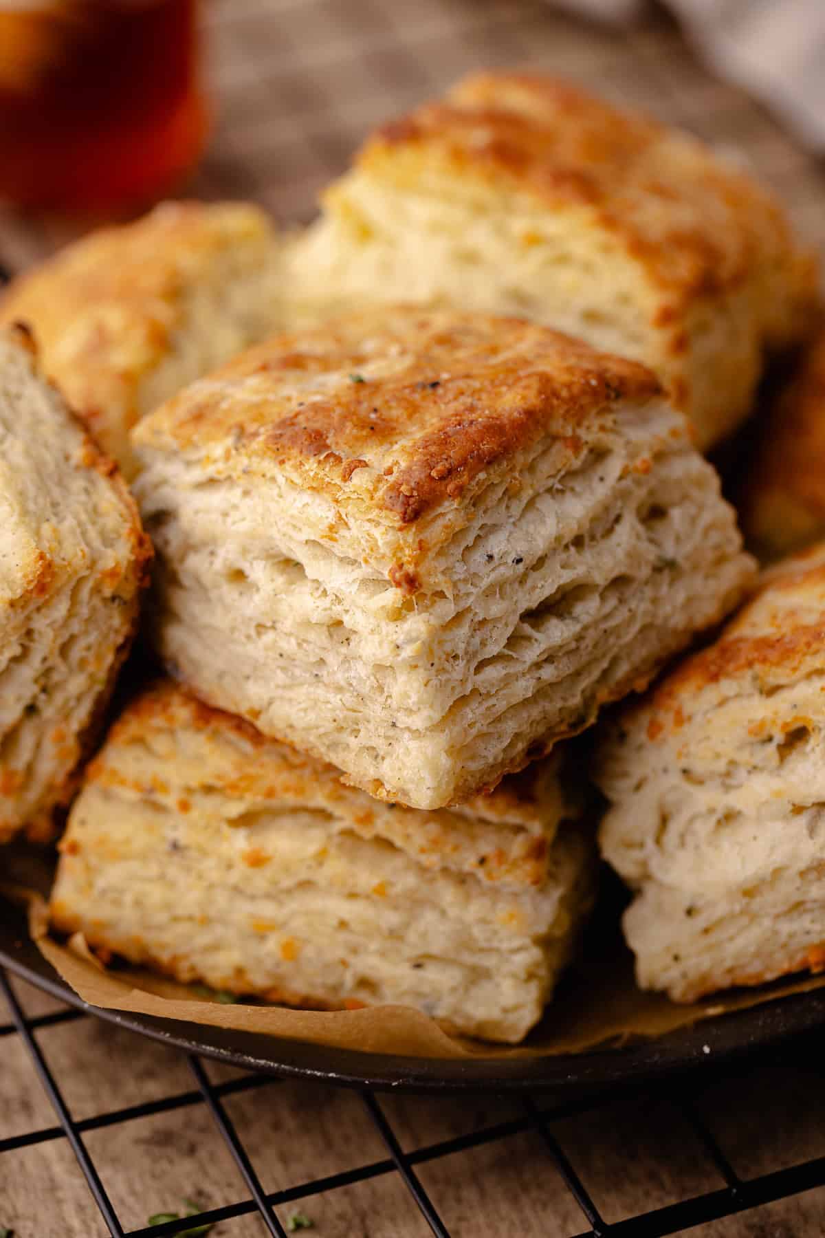 Tall and flaky Parmesan Black Pepper Thyme Biscuits sitting on a serving tray.