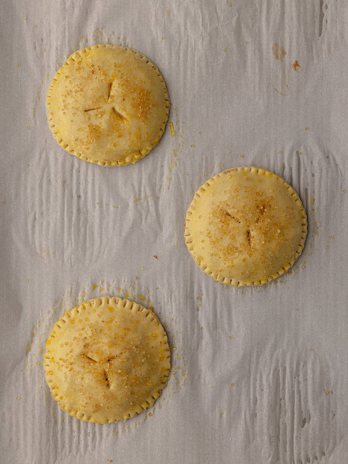 Unbaked Puff pastry apple hand pies are sitting on a baking sheet.