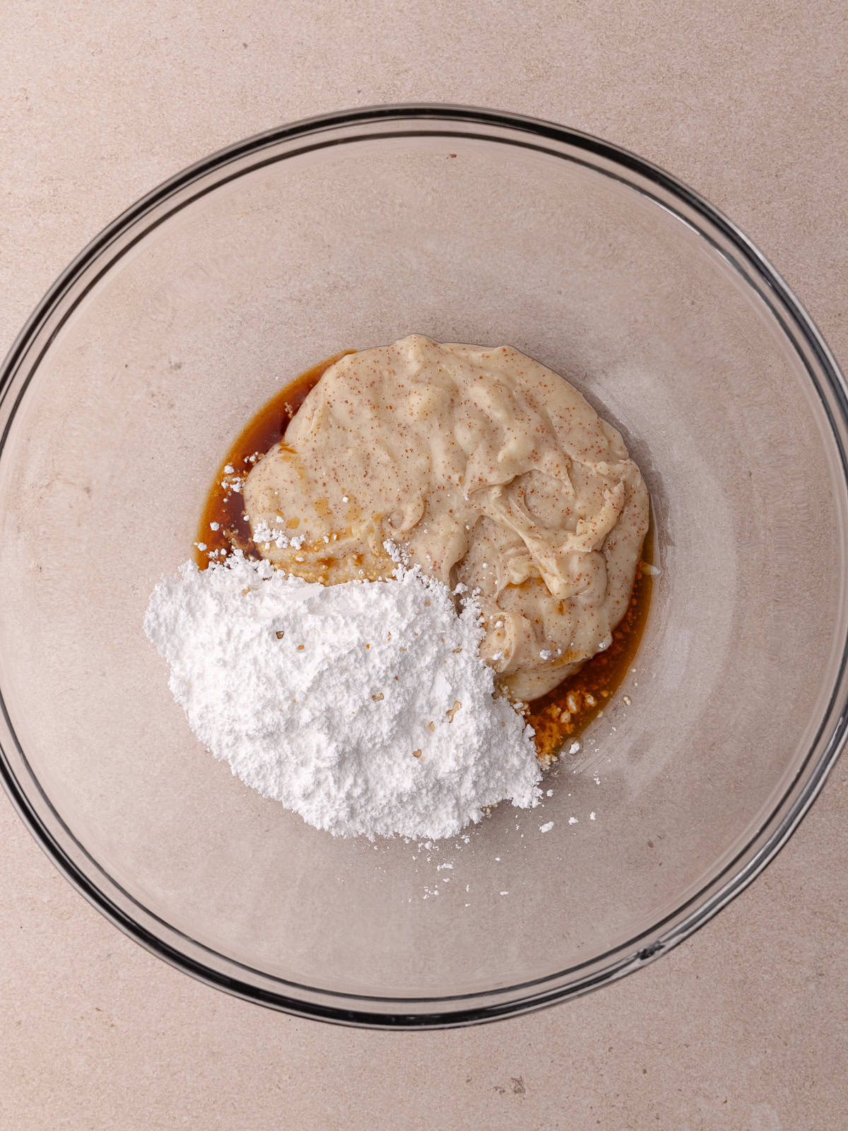 Softened brown butter, powdered sugar, maple extract and vanilla extract are sitting in a large mixing bowl.