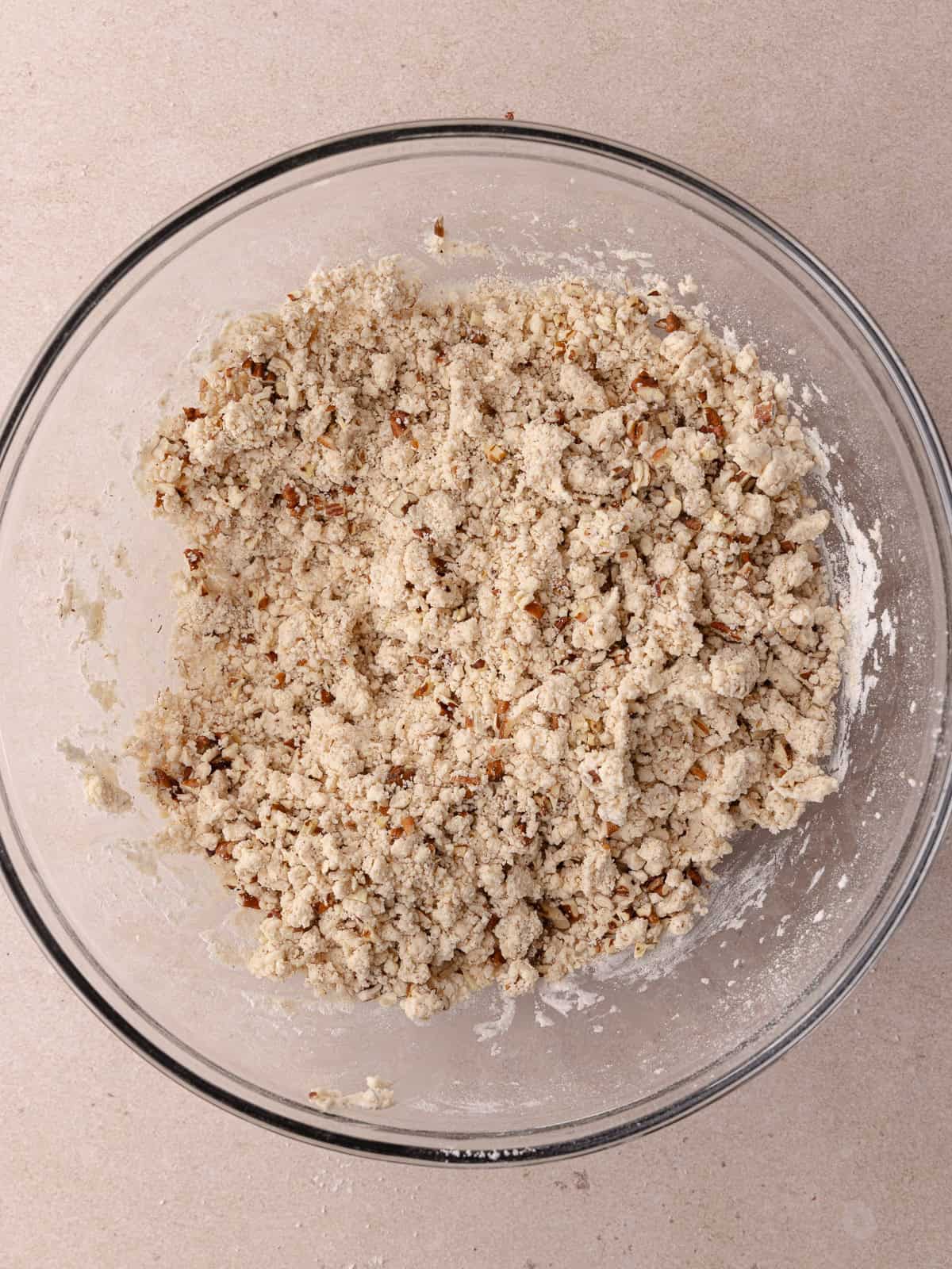 Brown butter pecan shortbread cookie dough is in a large glass mixing bowl.