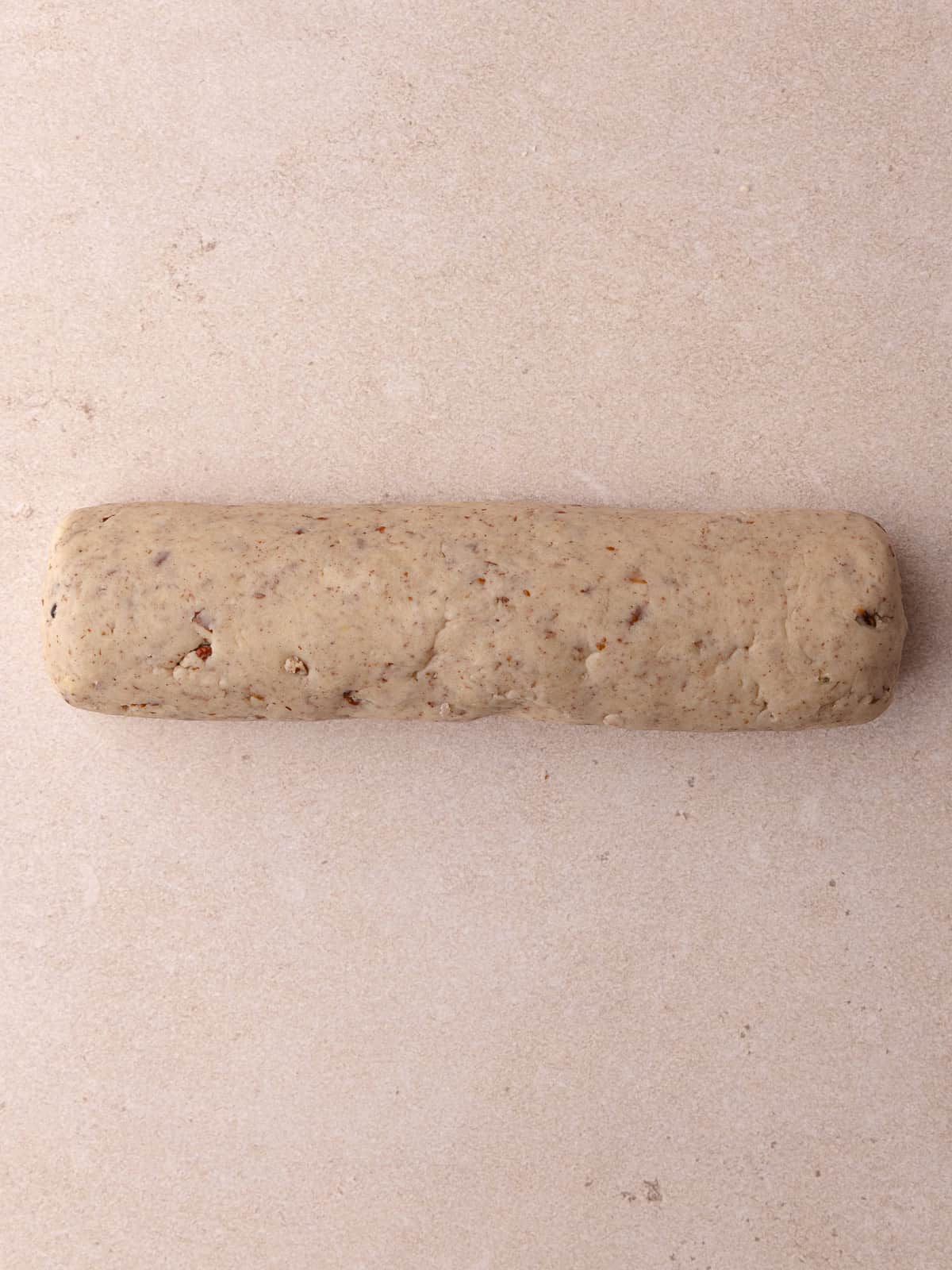 Brown butter pecan shortbread cookie dough is shaped into a log.