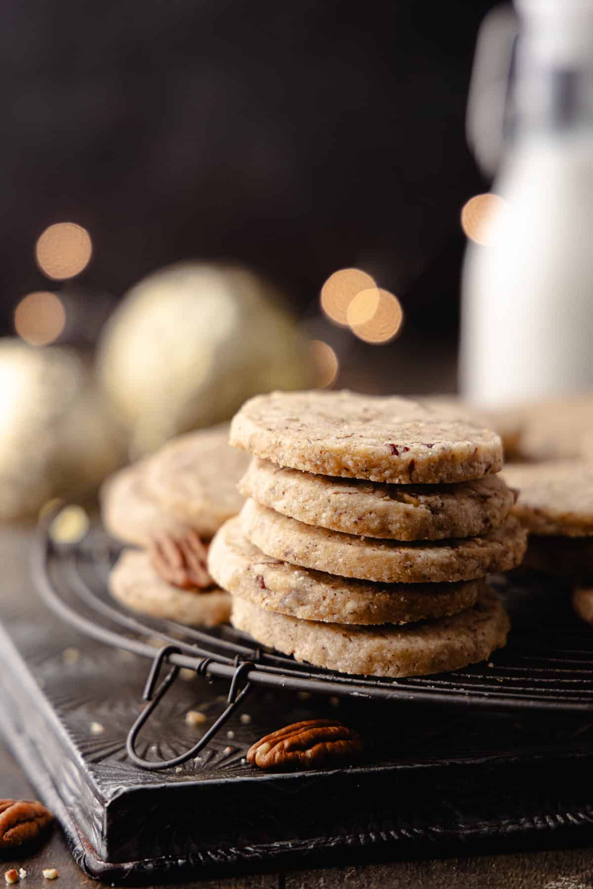 Brown butter pecan cookies with maple and cinnamon, stacked and sitting on a wire rack.