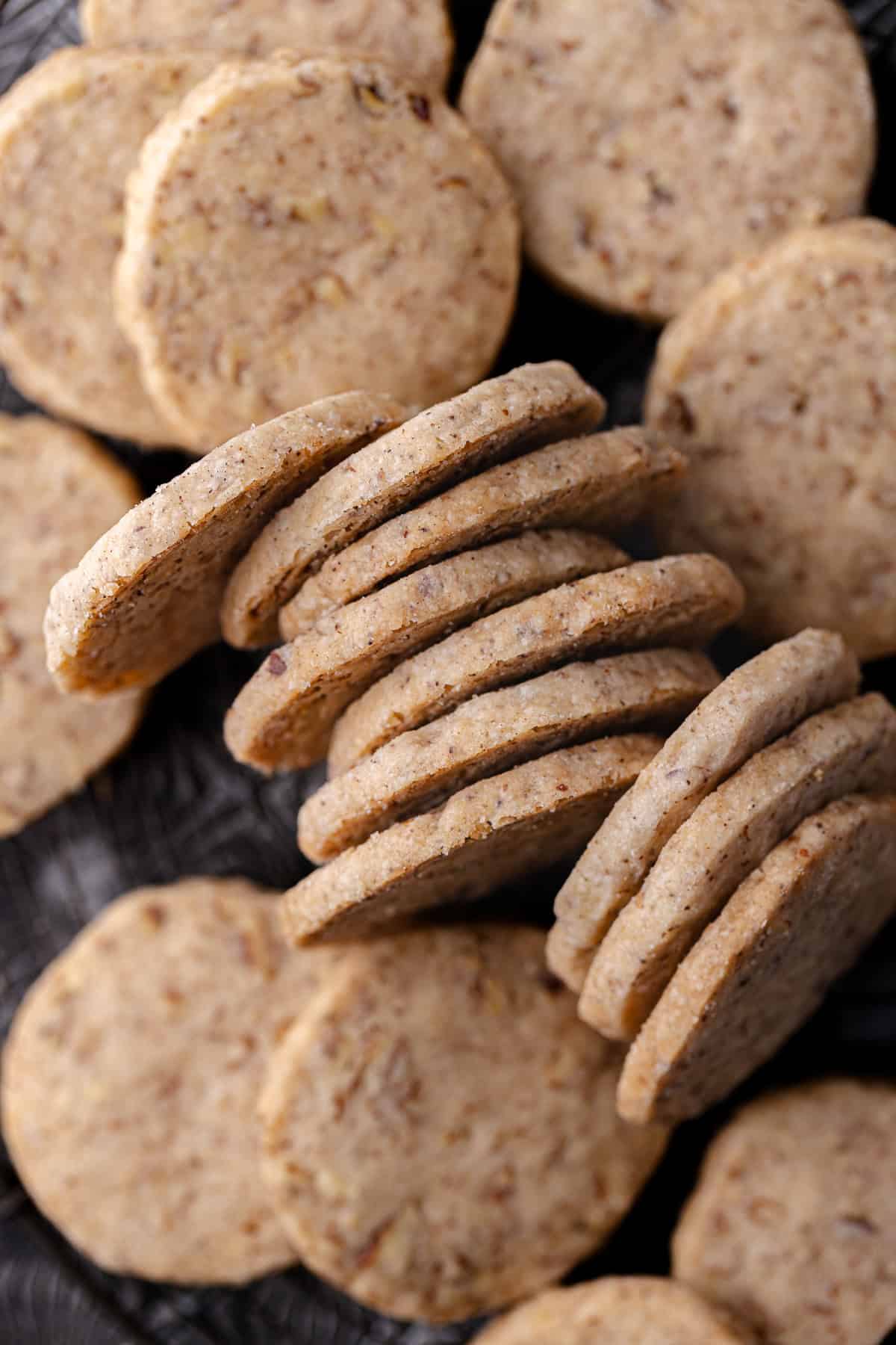 Brown butter pecan cookies with maple and cinnamon, stacked and sitting on a wire rack.