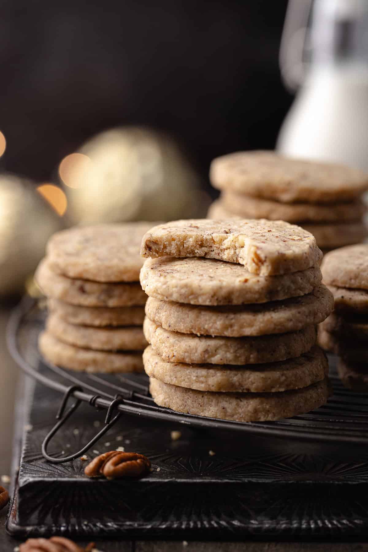 Brown butter pecan cookies with maple and cinnamon, stacked and sitting on a wire rack.