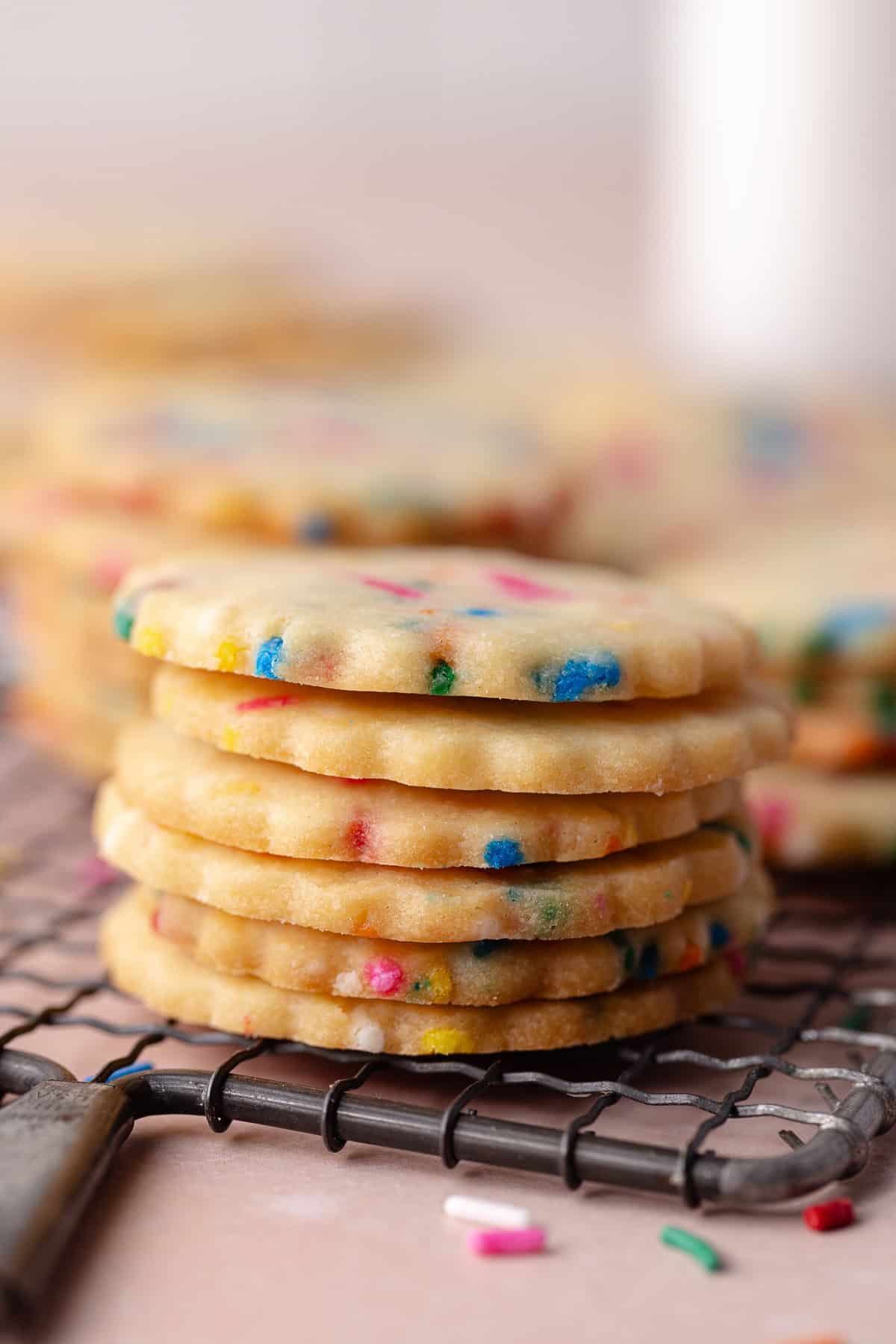 Stack of funfetti shortbread cookies are on a small wire rack.