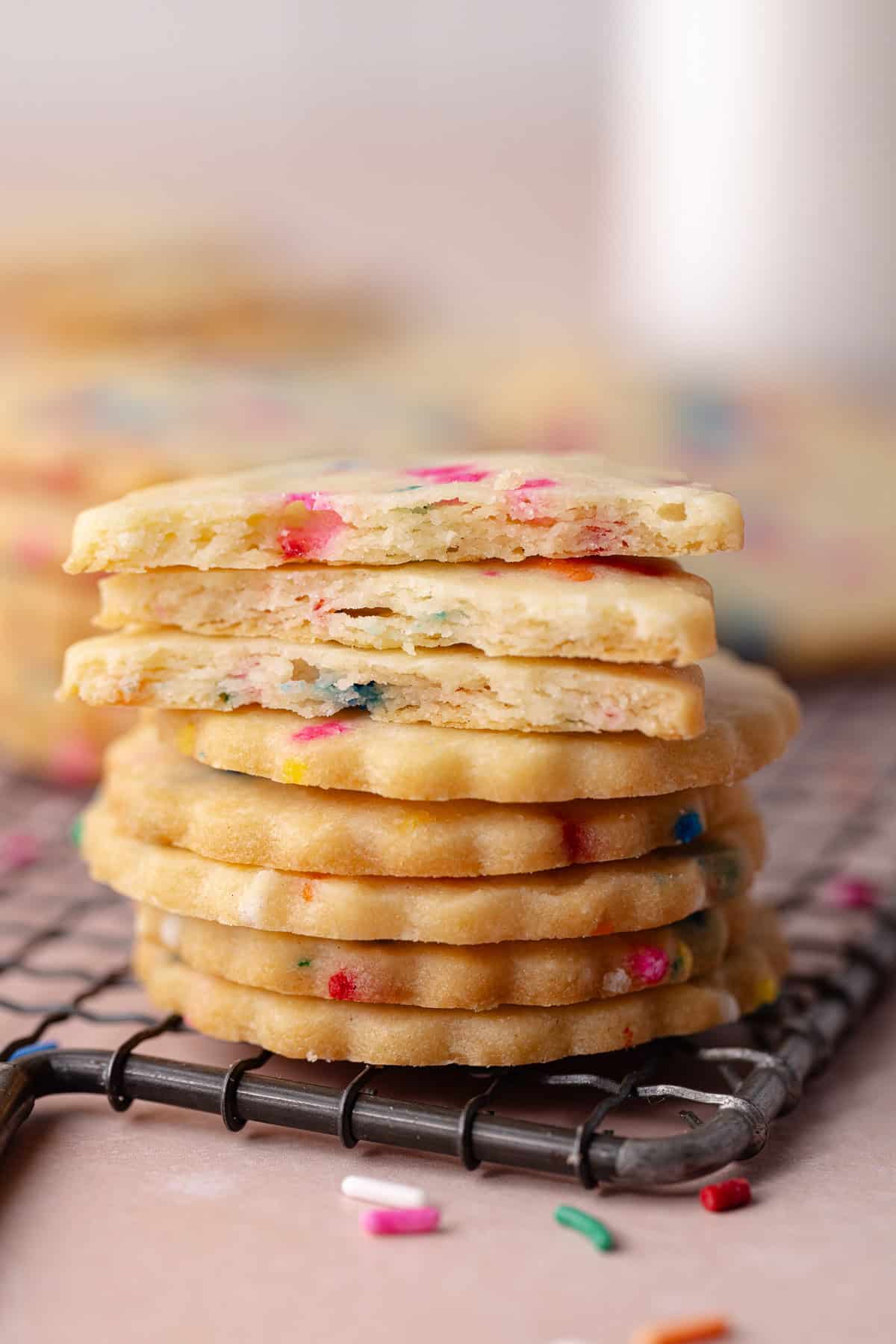 Stack of funfetti shortbread cookies are on a small wire rack.