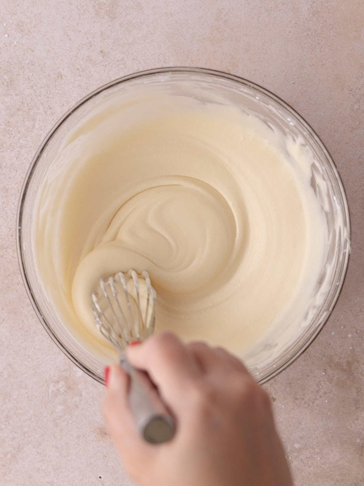 Cream cheese glaze whisked in a medium glass bowl.