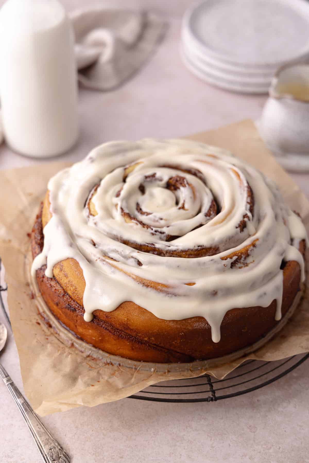 Giant cinnamon roll cake made with tangzhong milk bread brioche dough, sitting on a wire rack.