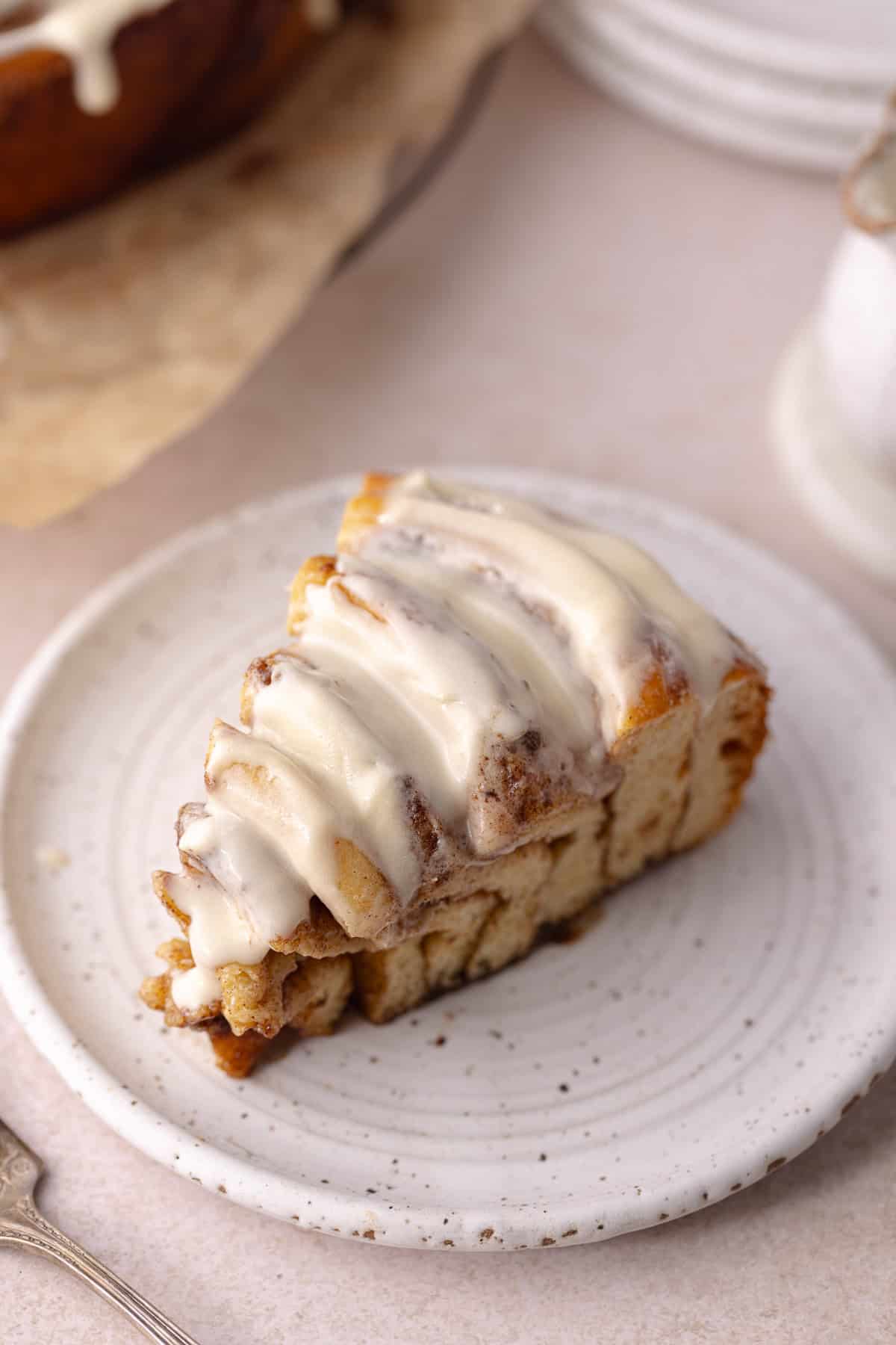 A slice of giant cinnamon roll cake made with tangzhong milk bread brioche dough, sitting on a dessert plate.