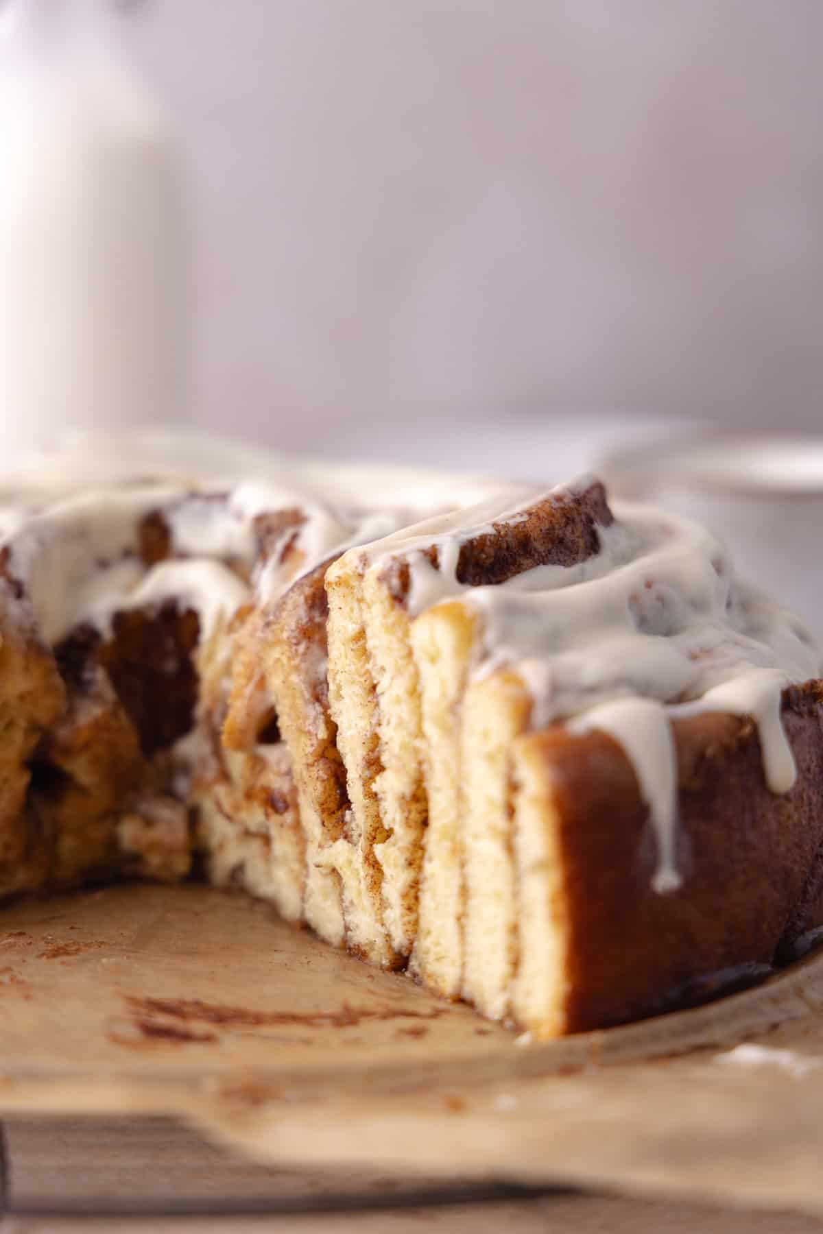 Giant cinnamon roll cake made with tangzhong milk bread brioche dough, sitting on a wire rack exposing layers.