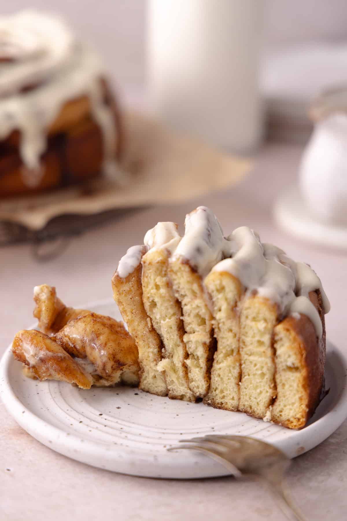 A slice of giant cinnamon roll cake made with tangzhong milk bread brioche dough, sitting on a dessert plate.