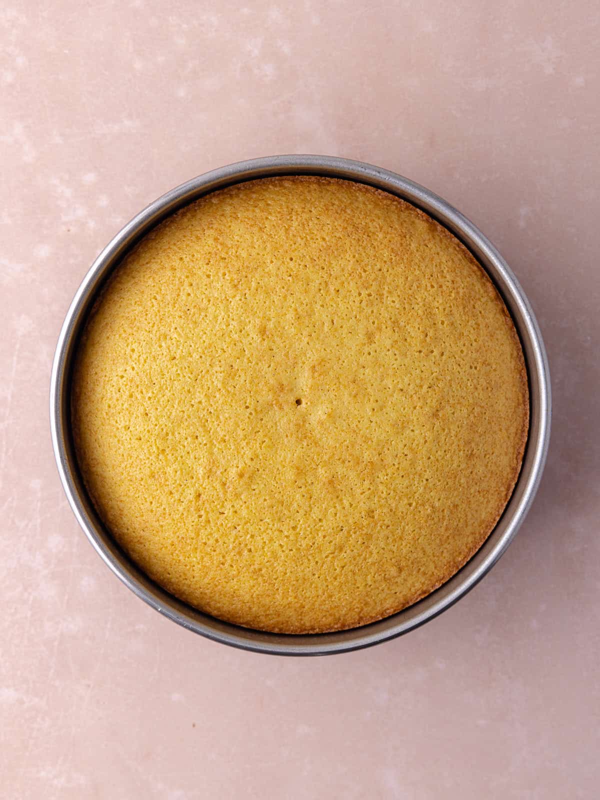 Baked grapefruit olive oil cake is pulled out of the oven and sitting in the cake pan.