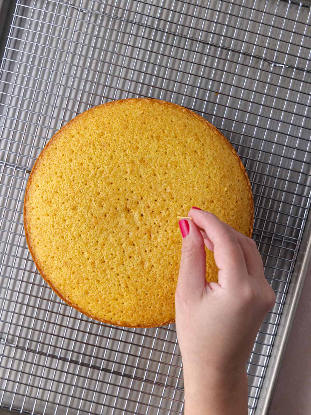 A small toothpick is used to prick holes all over the grapefruit olive oil cake.