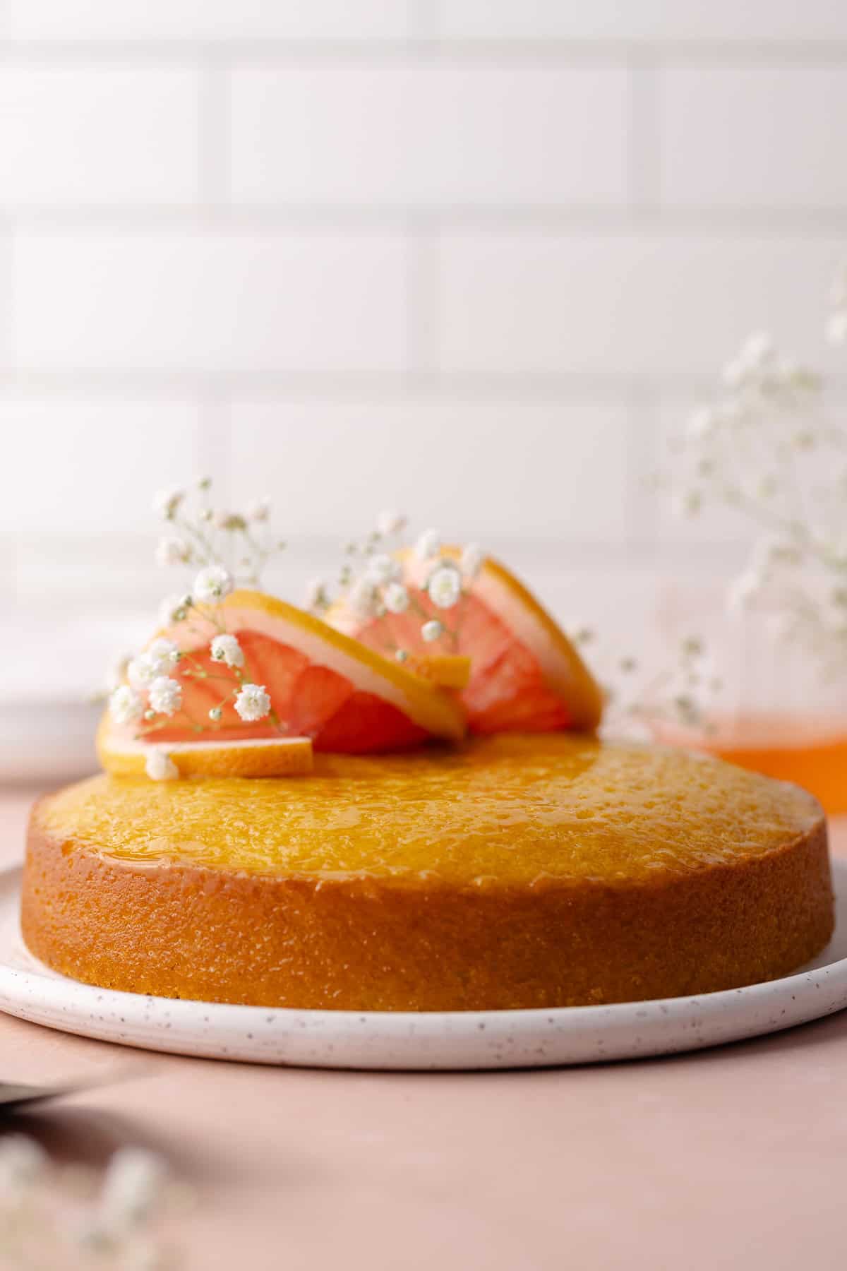 Soft and moist polenta grapefruit olive oil cake decorated with grapefruit slices and flowers.