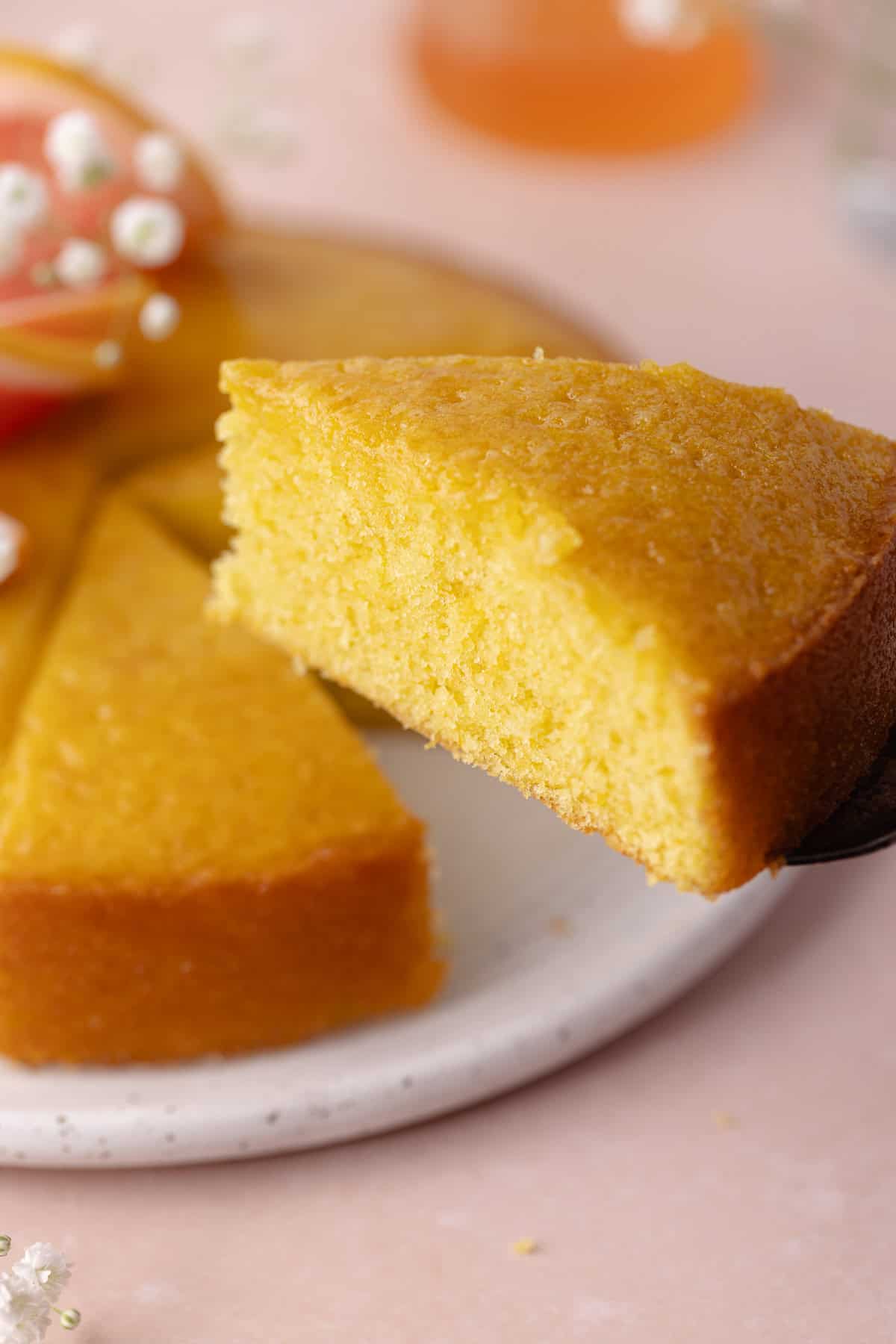 A slice of soft and moist polenta grapefruit olive oil cake on a cake server.