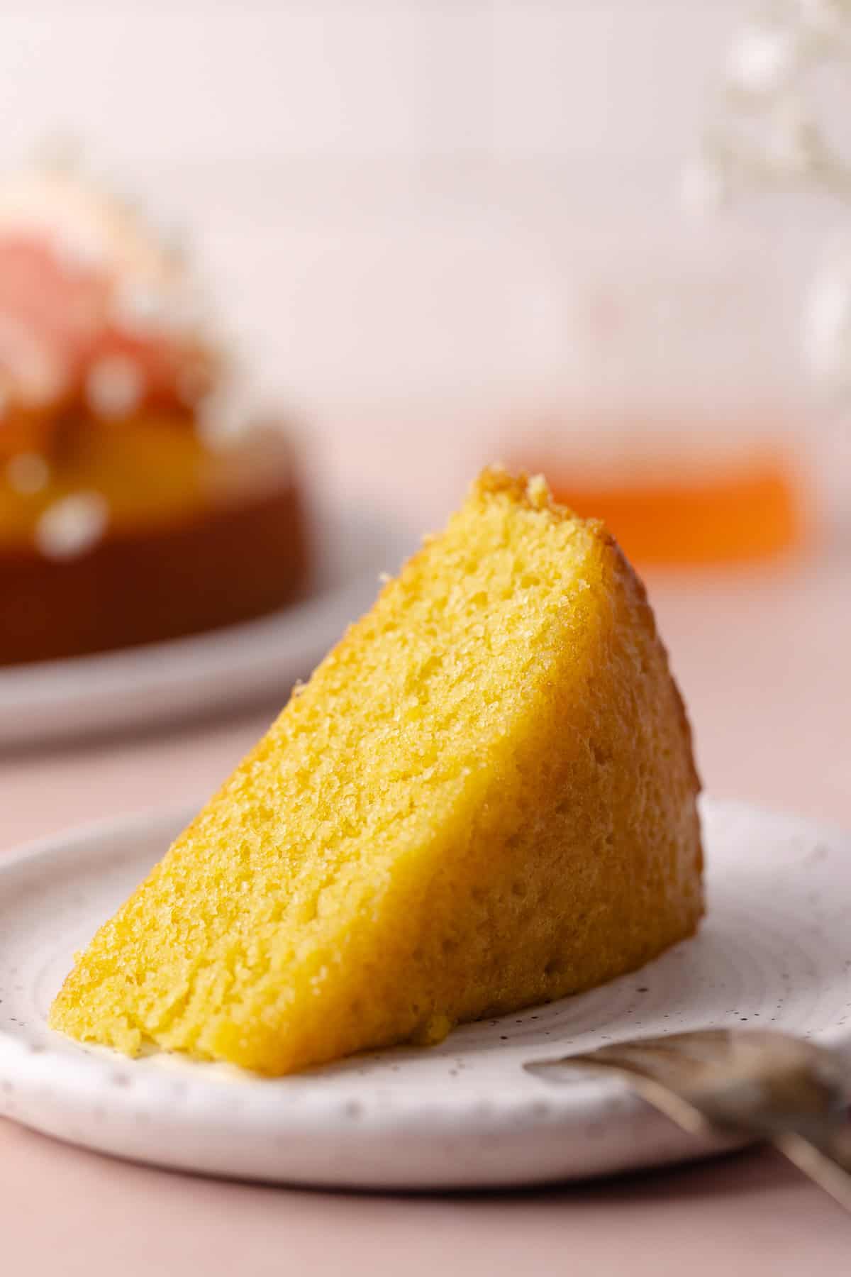 A slice of soft and moist polenta grapefruit olive oil cake sitting on a dessert plate.