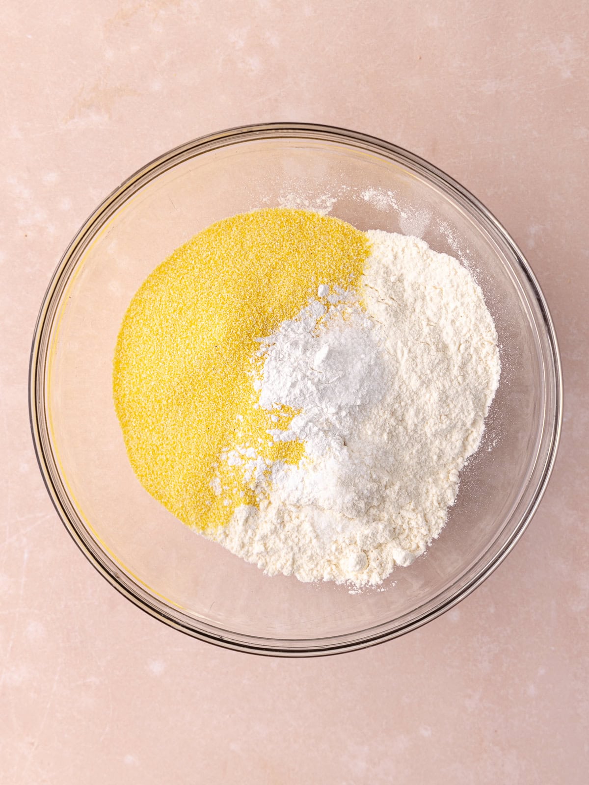 All-purpose flour, polenta (cornmeal), baking powder and salt are added to a medium glass mixing bowl.