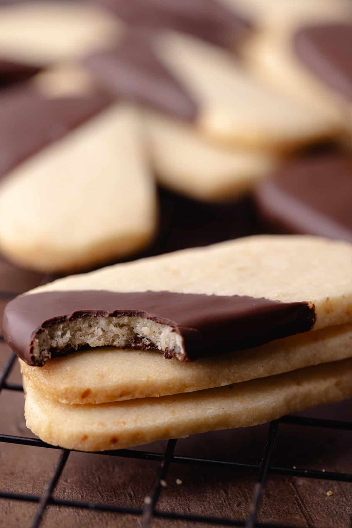 Macadamia nut shortbread also known as, hawaiian shortbread cookies are dipped in chocolate and sitting on a wire rack.