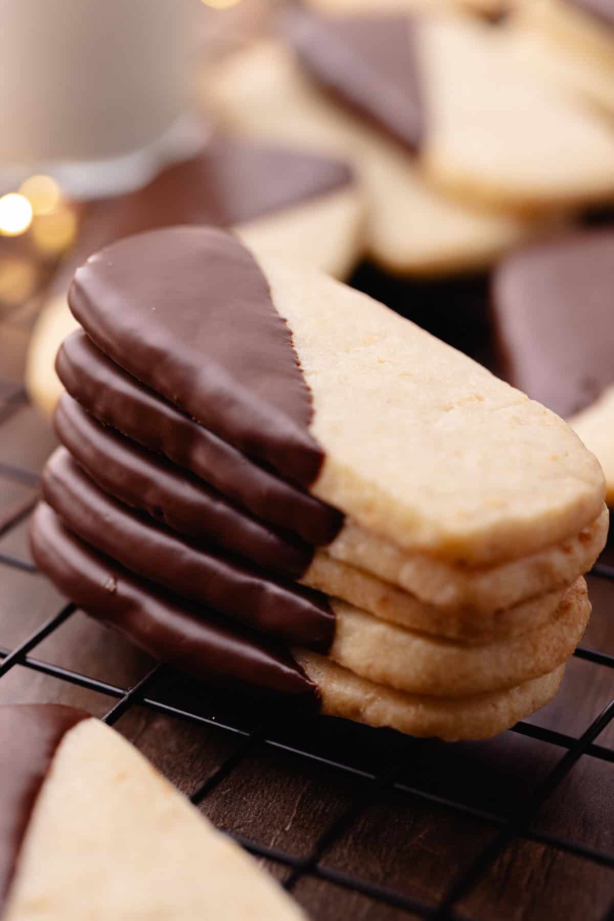 A stack of macadamia nut shortbread also known as, hawaiian shortbread cookies are dipped in chocolate and sitting on a wire rack.